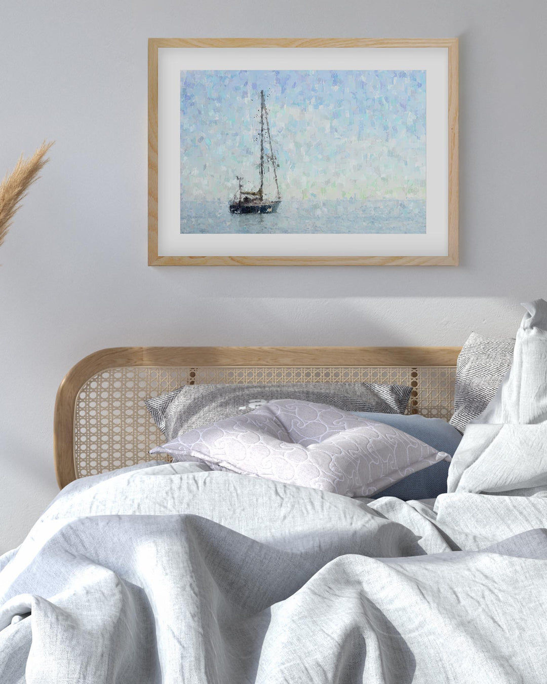Framed artwork of a sailboat on a wall above a bed with white bedding.