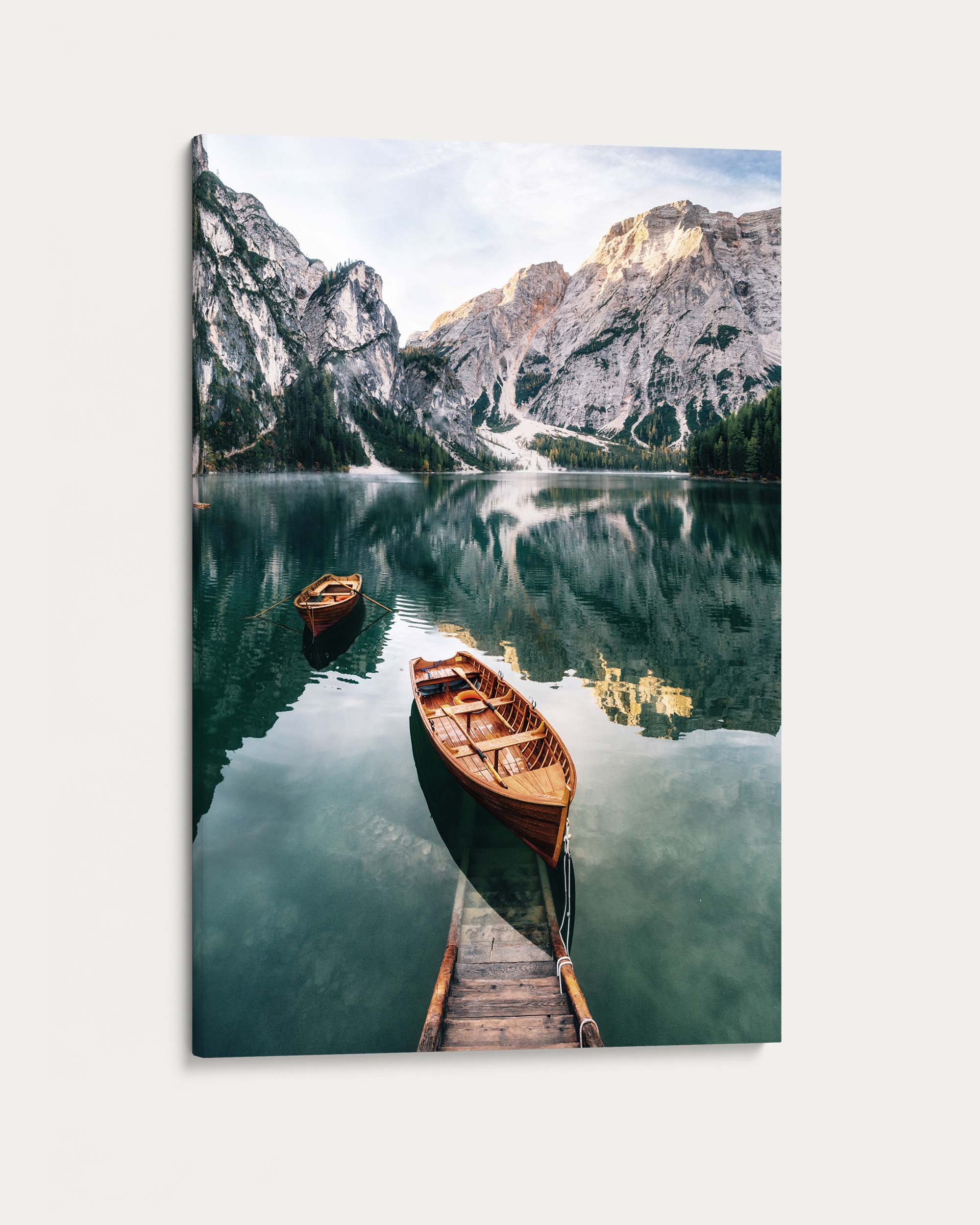 Two wooden boats on a calm lake with mountains in the background