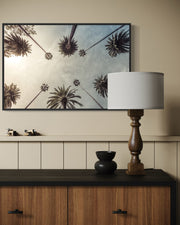 Decorative setup with a framed artwork, lamp, and small sculptures on a wooden cabinet.