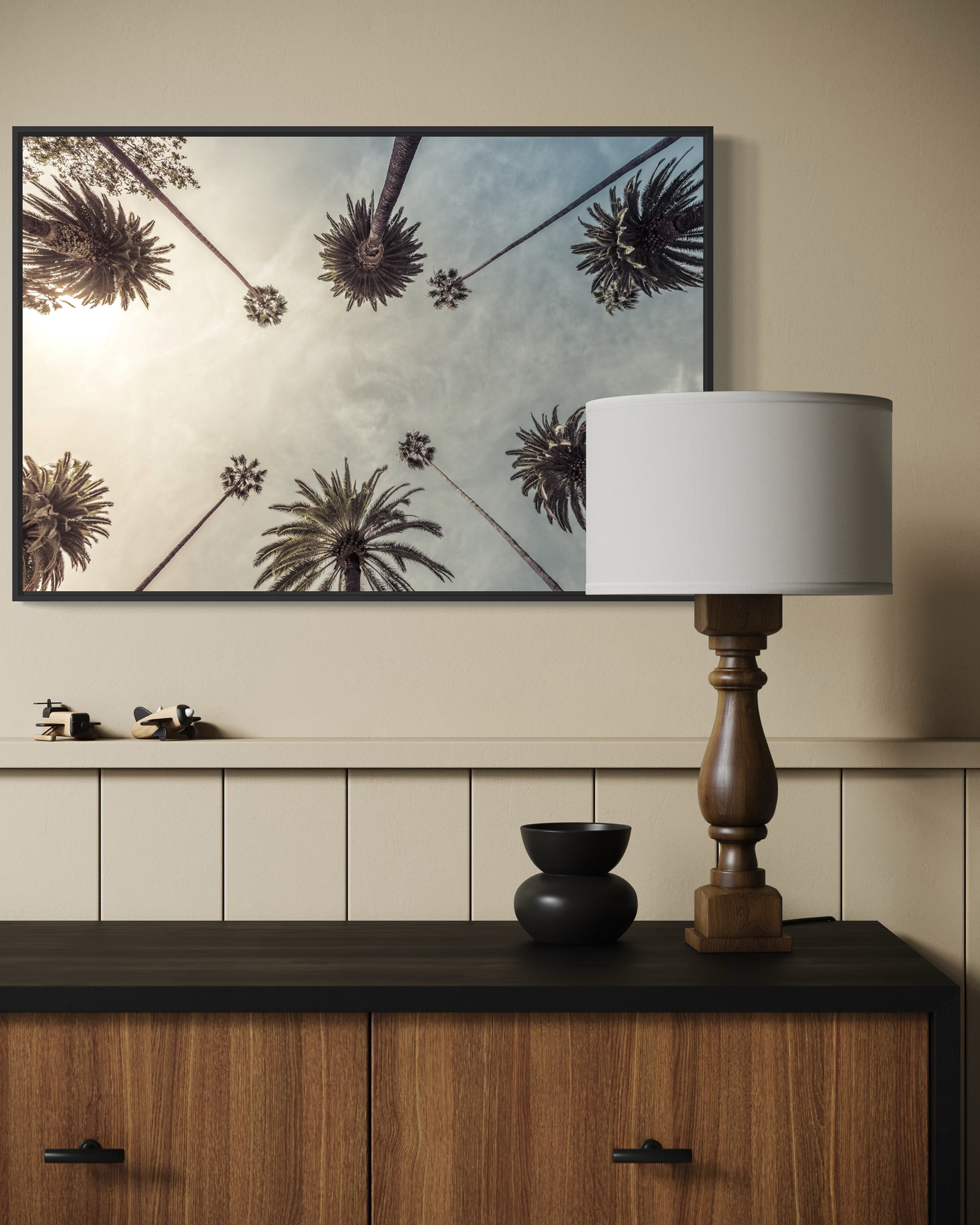 Decorative setup with a framed artwork, lamp, and small sculptures on a wooden cabinet.