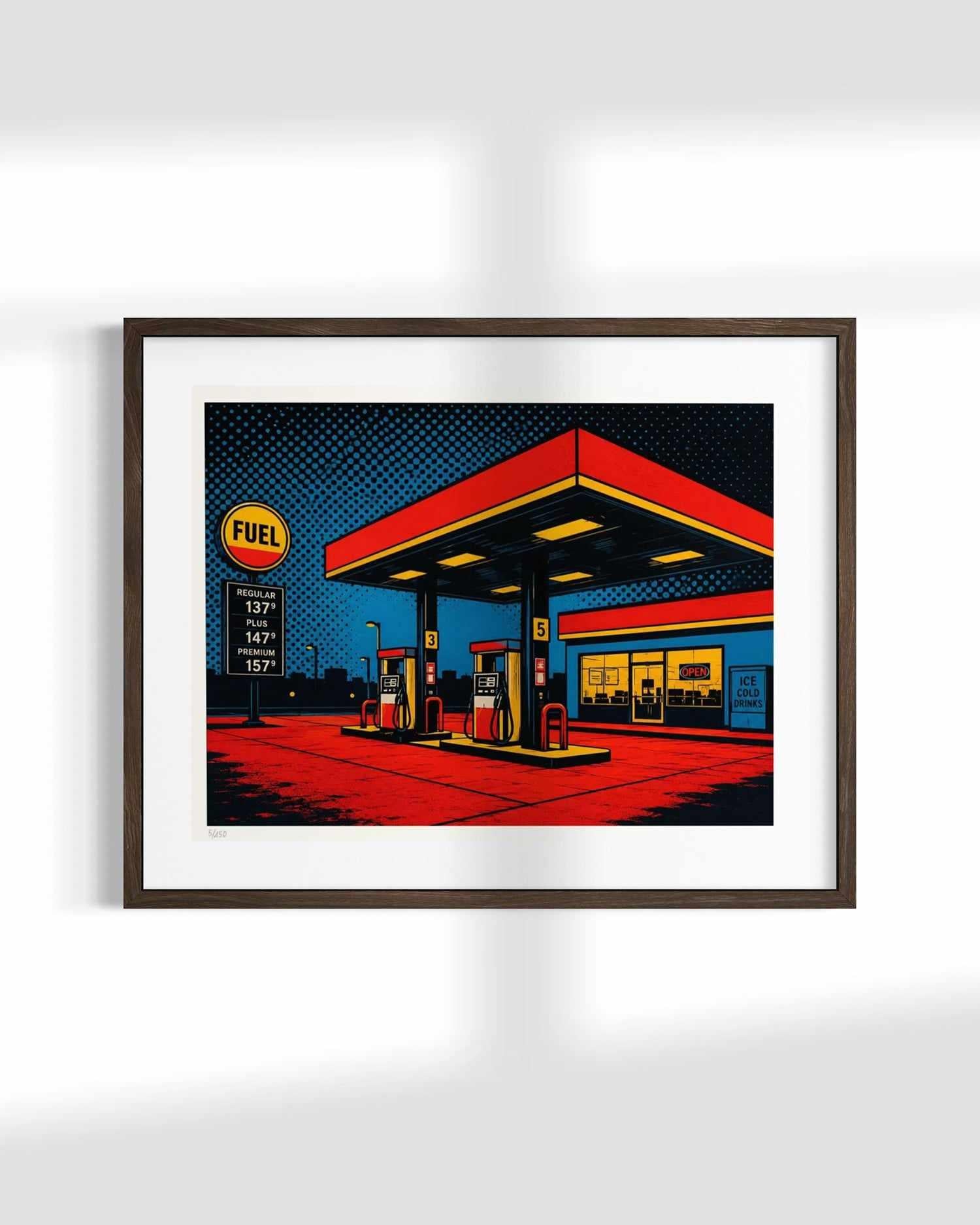A framed pop art print depicting a stylized gas station at night, featuring bold red, yellow, blue, and black colors, mounted on a white wall.