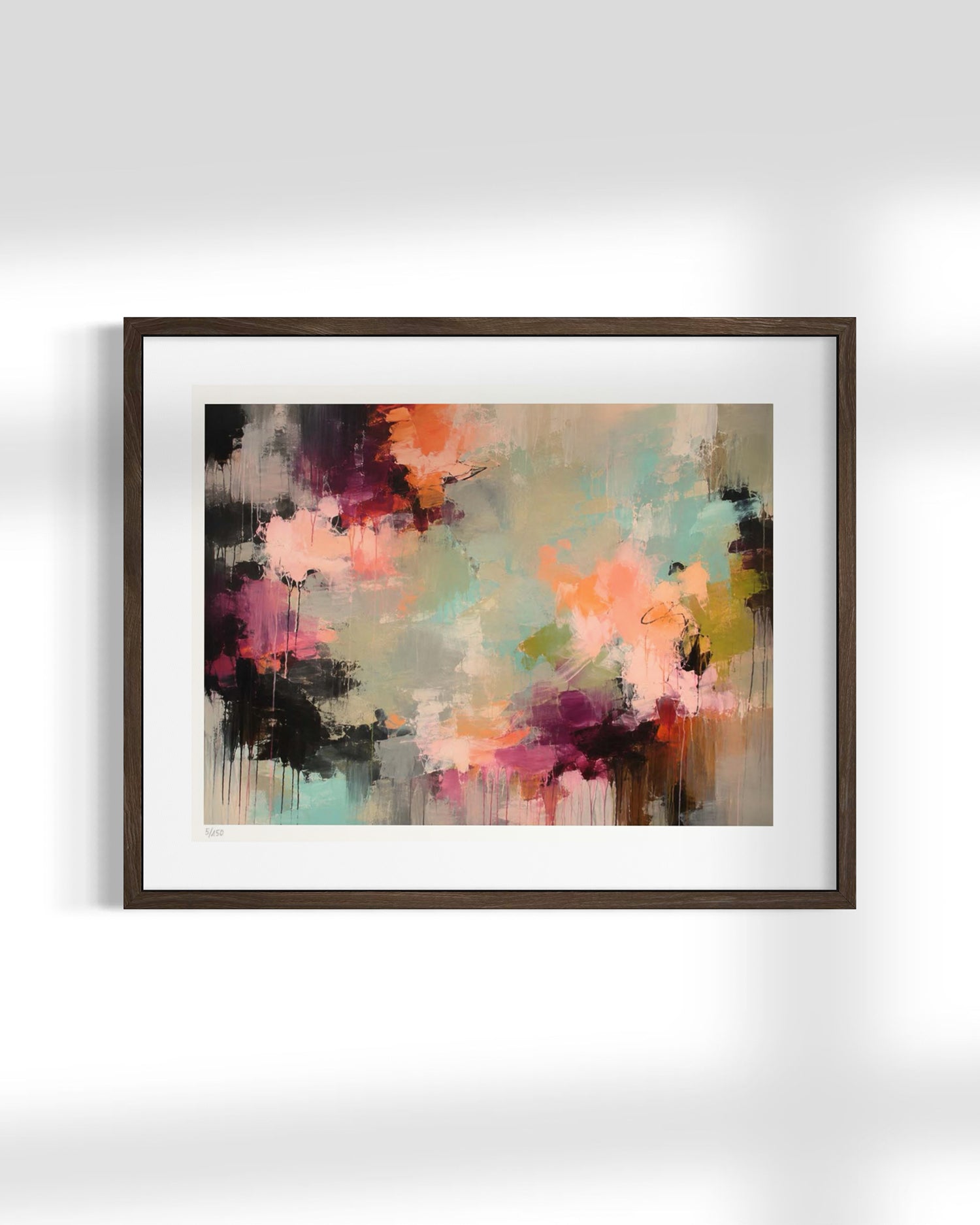 Framed abstract wall art hanging on a light gray wall, featuring a multicolor paint-splatter design with pink, orange, teal, purple, black, and beige tones inside a dark brown wooden frame with a white mat.