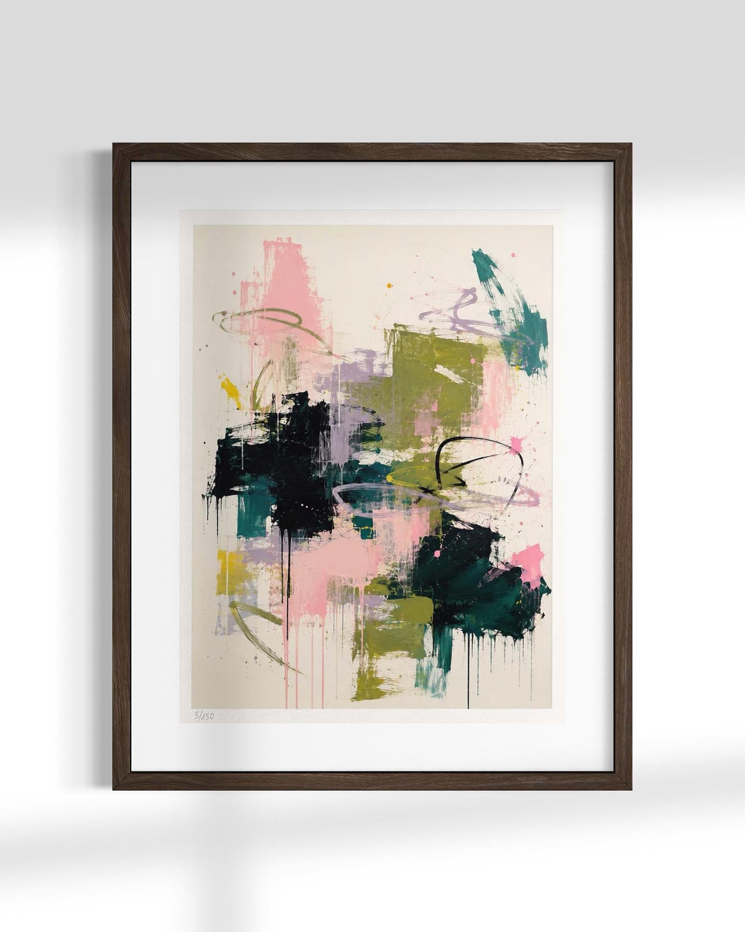 Framed abstract wall art print with expressive brushstrokes in pink, green, black, teal, and purple on a cream background, shown in a dark wood frame against a light gray wall.