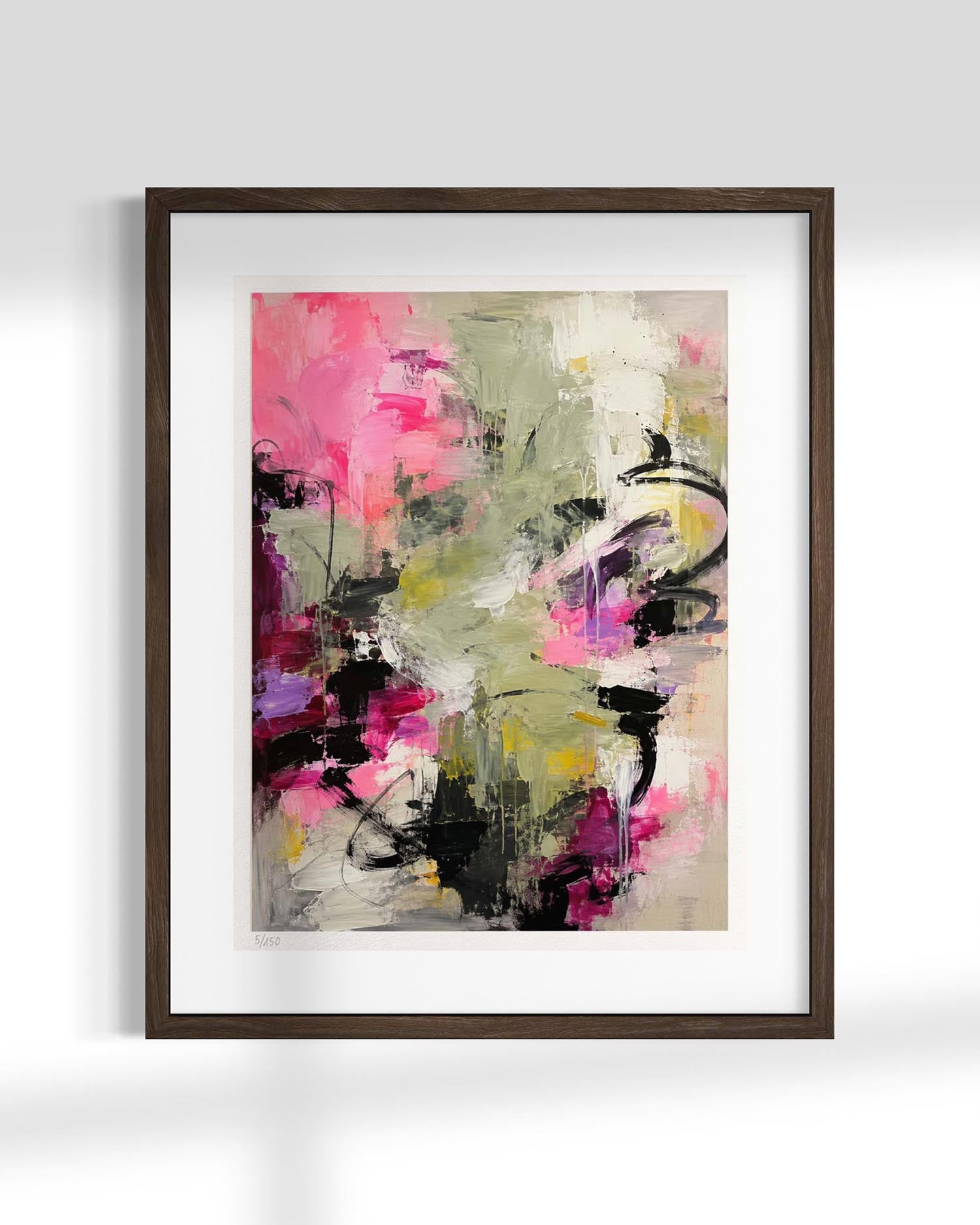 An abstract framed wall art print featuring expressive brushstrokes in pink, olive green, black, purple, and cream, presented in a dark brown frame with a white mat against a light gray wall.