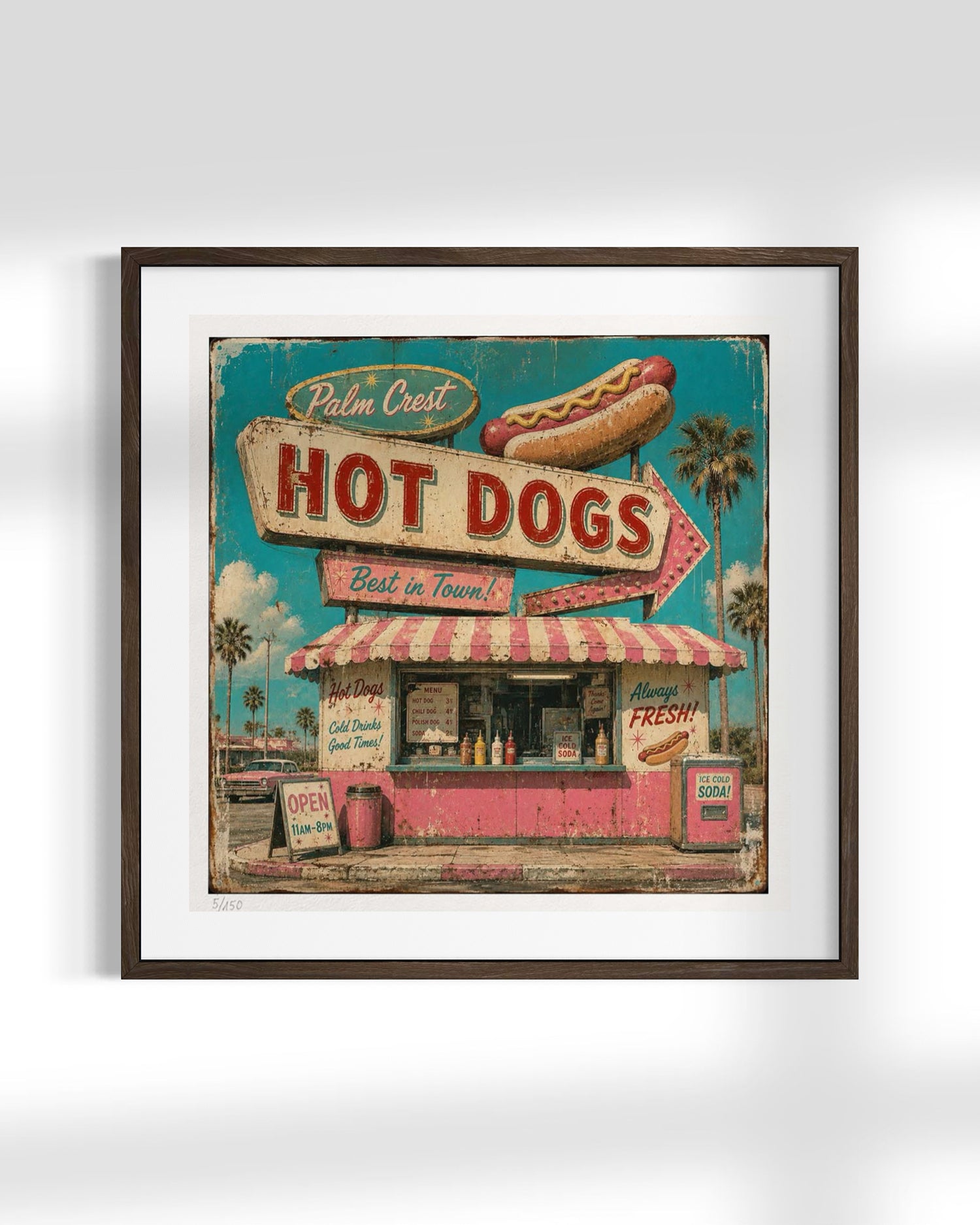 Framed vintage-style wall art featuring a retro hot dog stand with a large sign reading 'Palm Crest Hot Dogs,' a hot dog illustration, and a pink-and-white striped awning, shown in a dark wood frame against a light gray background.