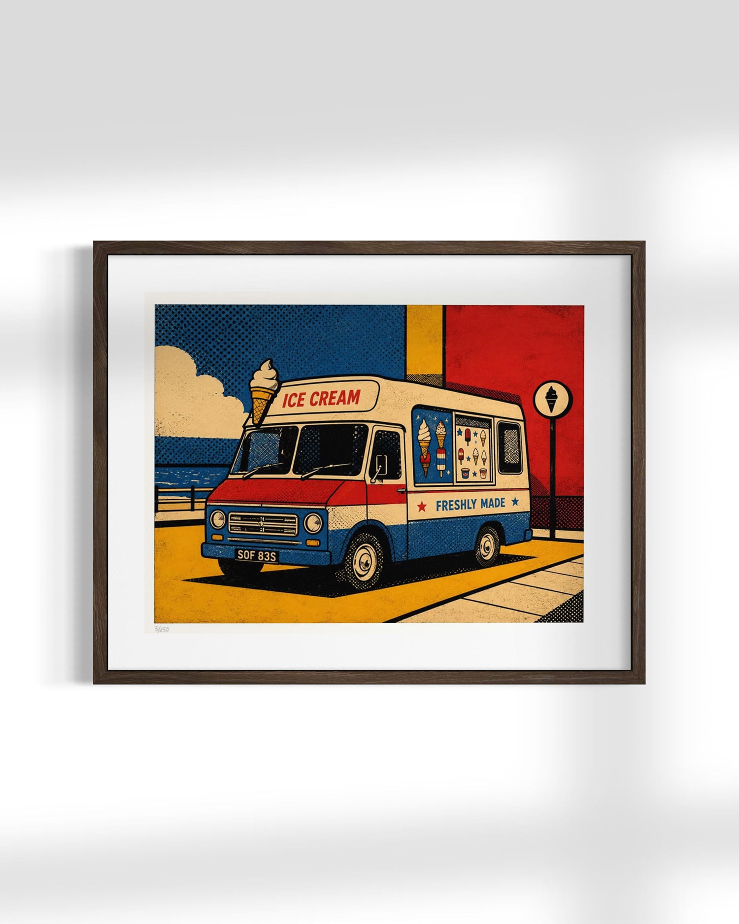 Framed pop-art style print of a retro ice cream truck, shown hanging on a light gray wall. The artwork features a cream, red, and blue truck with bold graphic elements and a yellow ground, enclosed in a dark brown frame with a white mat.