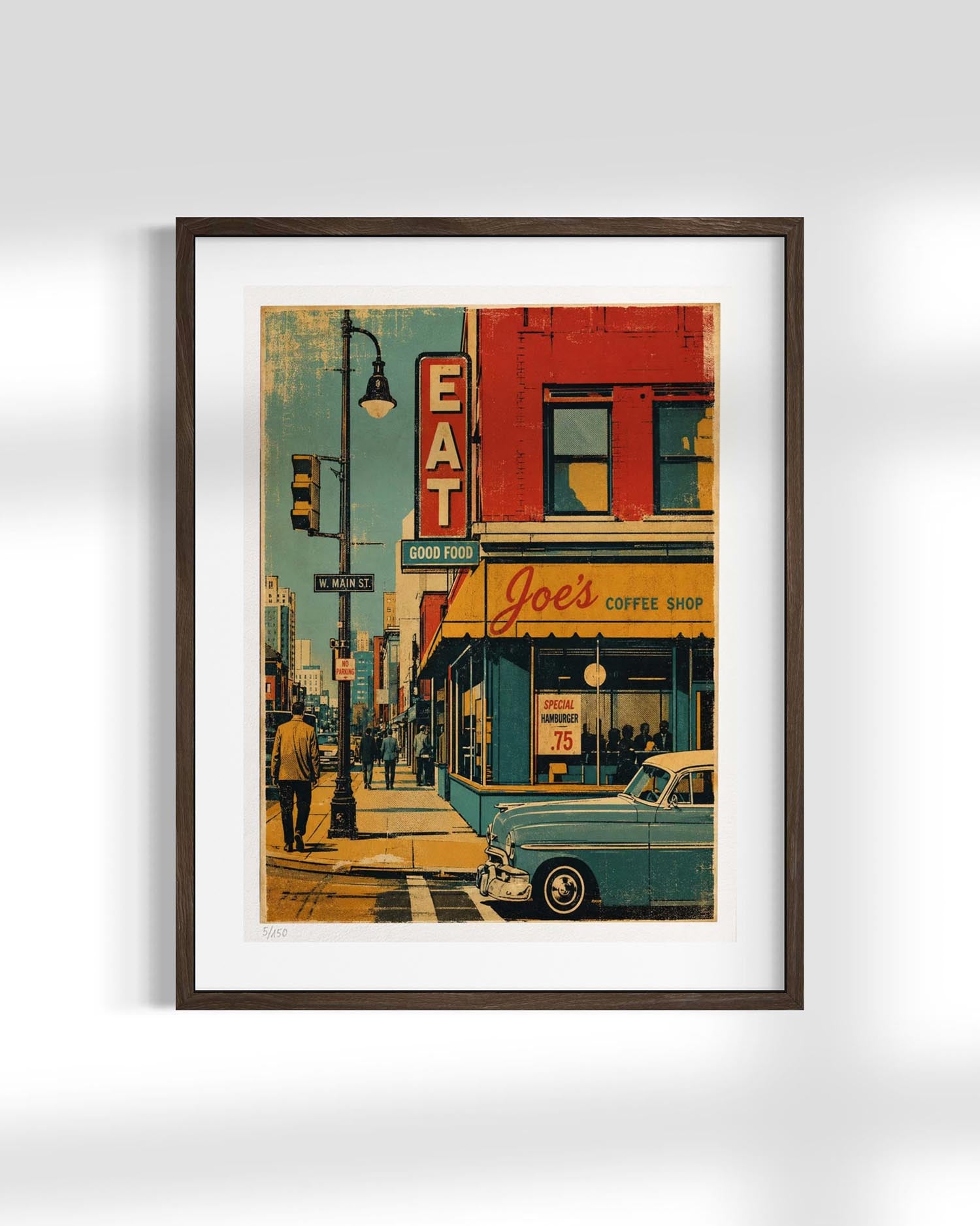 A framed vintage-style art print depicting a retro street scene with a teal car parked outside 'Joel's Coffee Shop,' a red building, and a streetlamp, shown against a light gray wall.