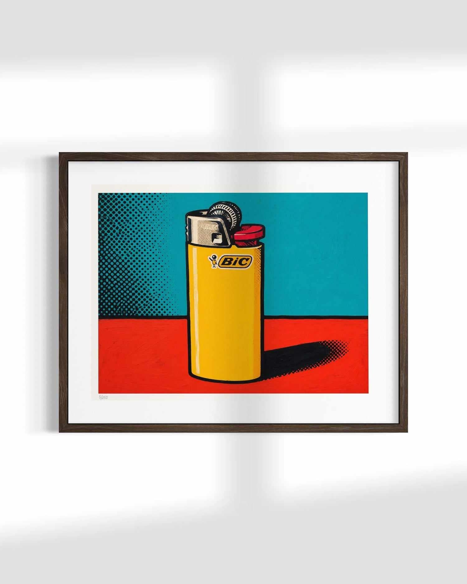 A framed pop-art style print featuring a yellow BIC lighter against a teal and red background, mounted on a white wall.