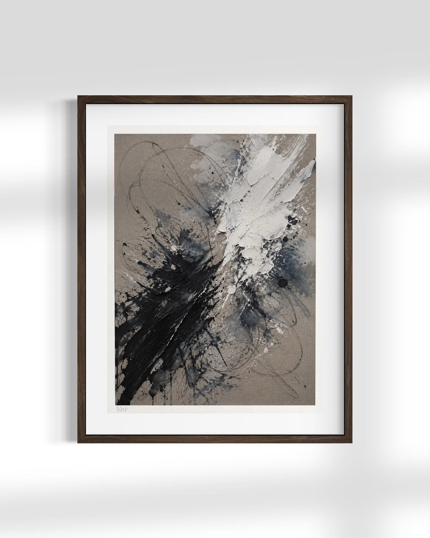 Framed abstract wall art featuring a dynamic black, white, and gray paint splatter design on a textured taupe background, presented in a dark wood frame with a white mat against a light gray wall.