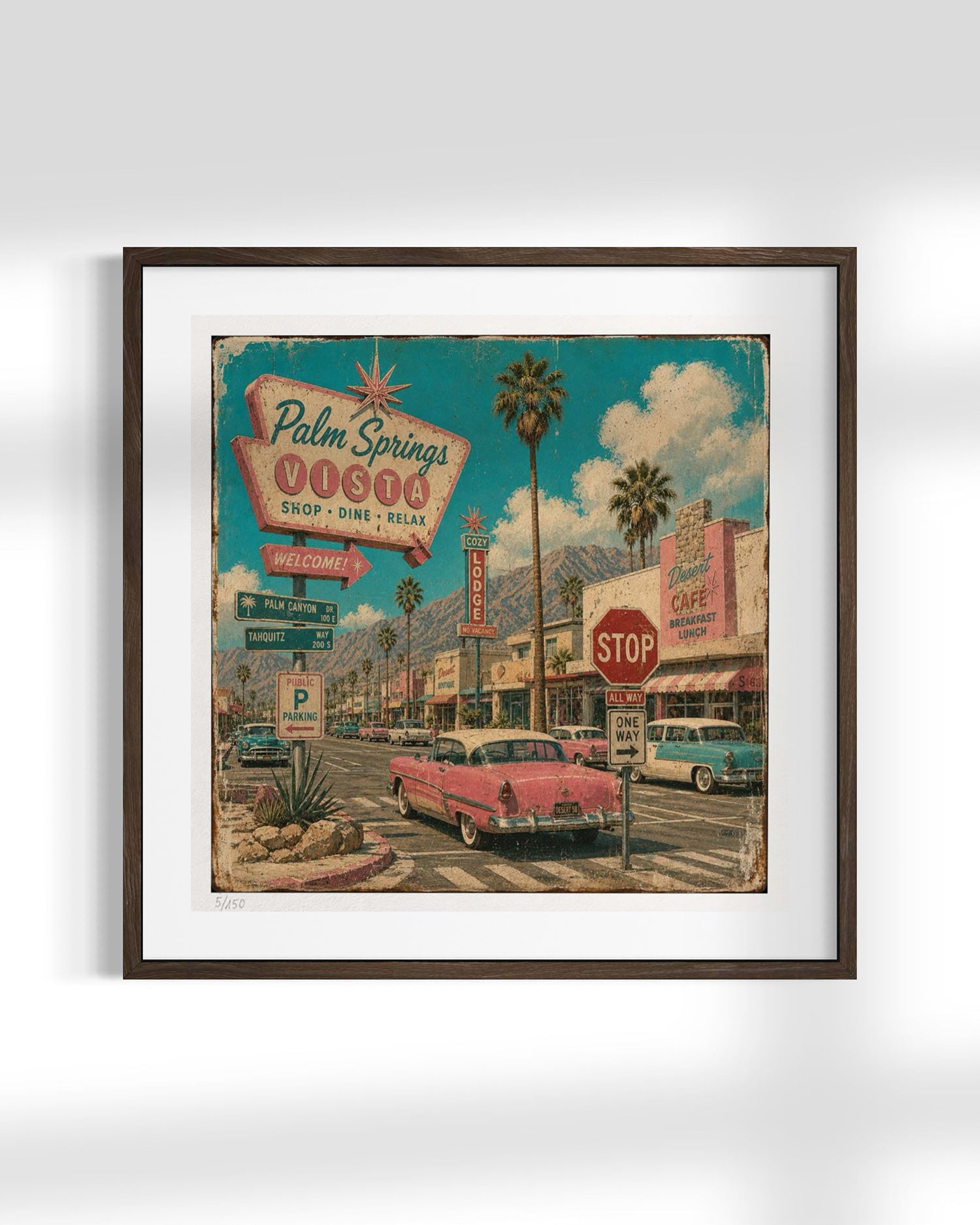 A framed art print depicting a retro 1950s Palm Springs street scene with vintage cars, palm trees, and a colorful sign, shown against a light gray background.