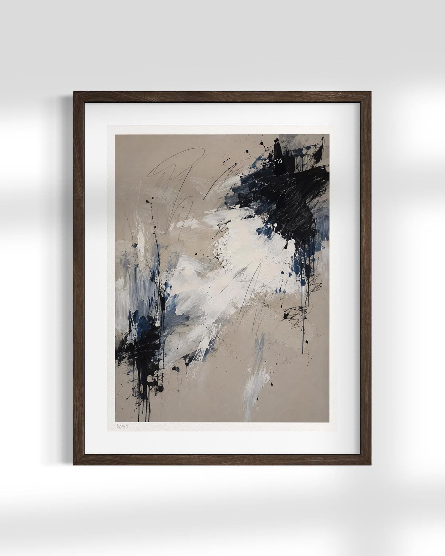 Framed abstract wall art featuring a beige background with expressive black, white, and blue paint splatters, presented in a dark brown frame against a light gray wall.