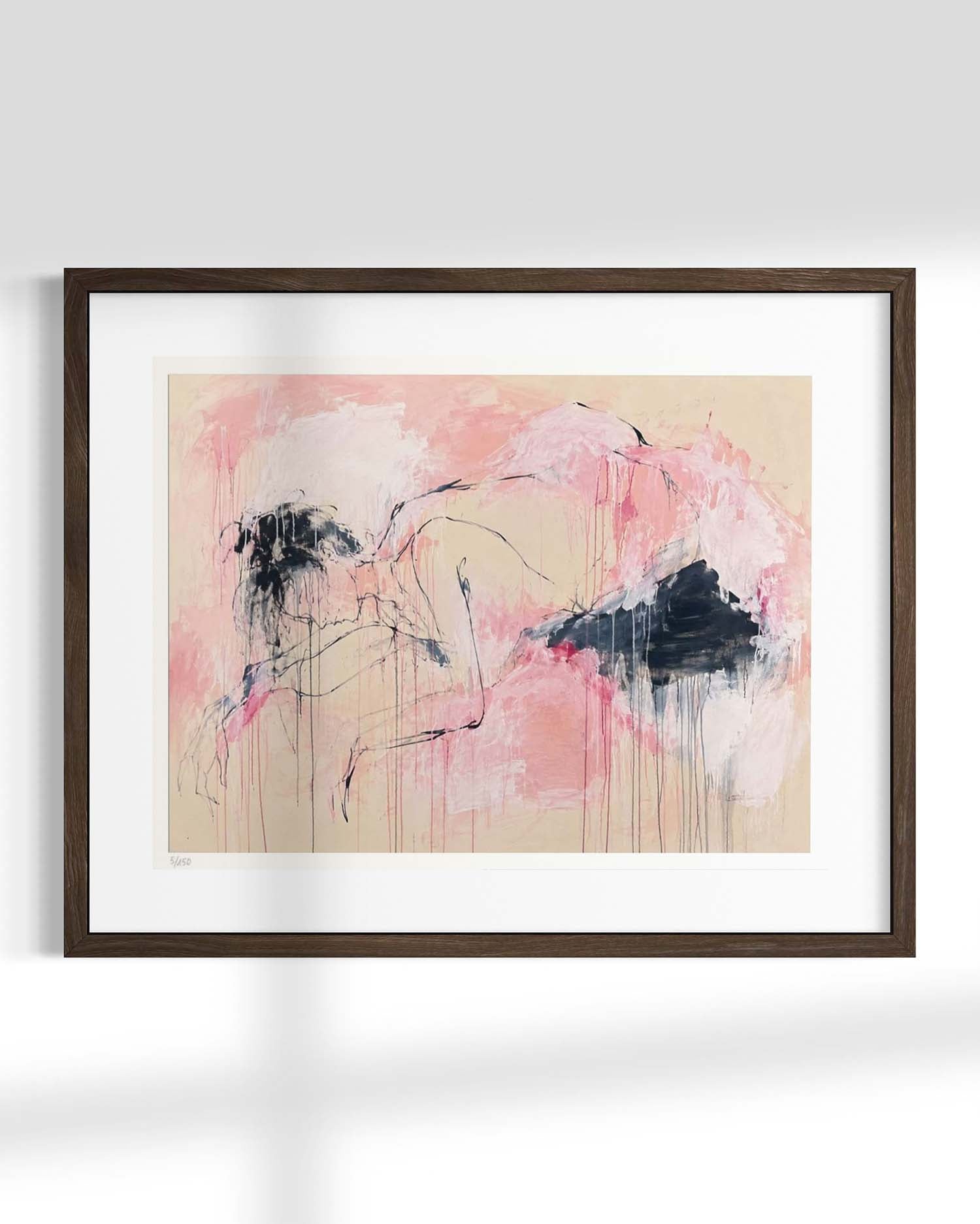 Framed abstract wall art hanging on a light gray wall, featuring a pink and beige composition with black and dark gray brushstrokes, set in a dark brown wooden frame with a white mat.