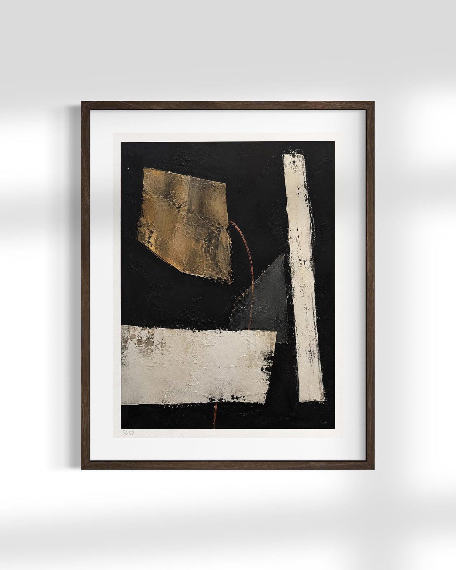 A framed abstract art print featuring a black background with textured white and gold geometric shapes, presented in a dark wood frame with a white mat against a light gray wall.