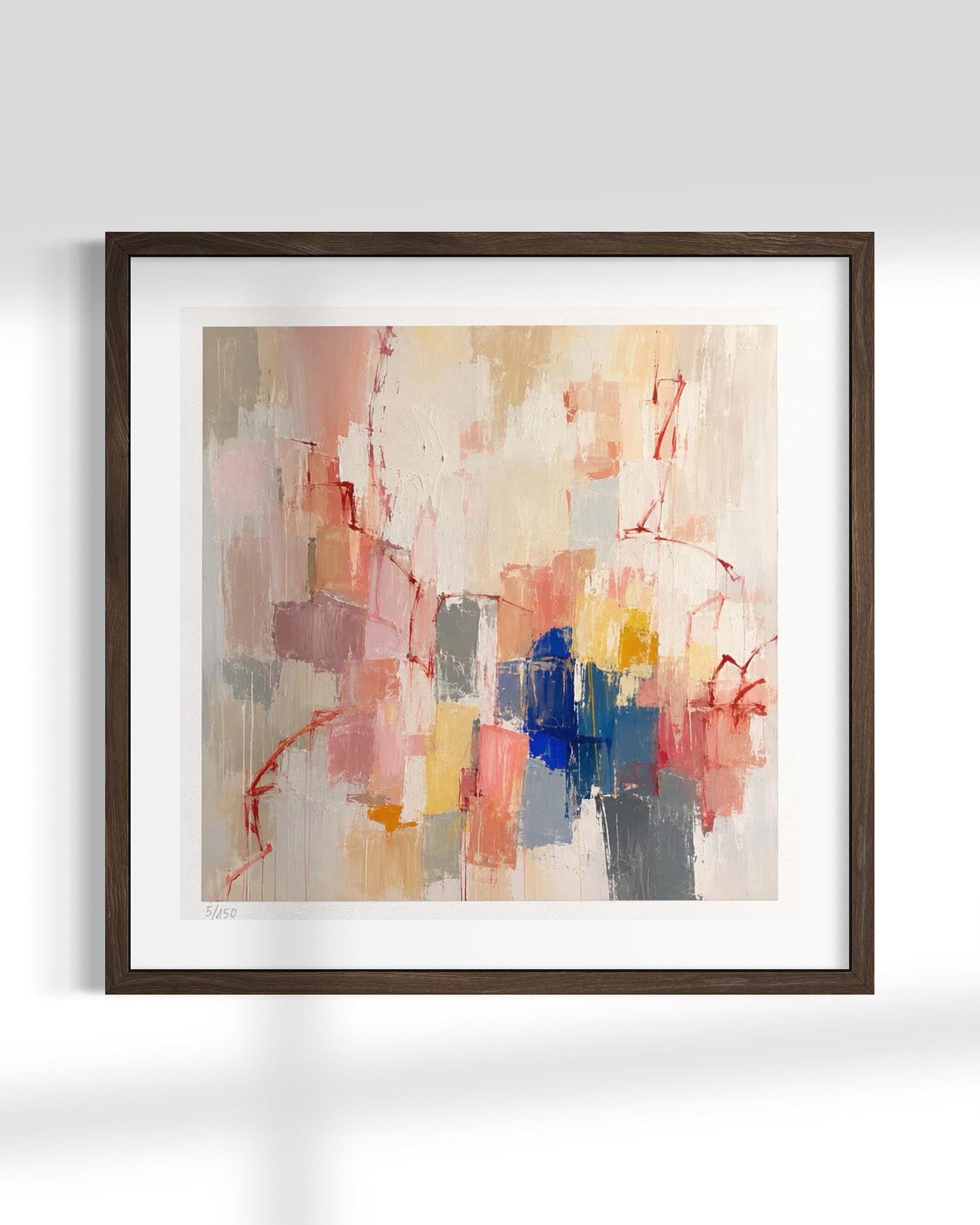 Framed abstract wall art featuring expressive brushstrokes in beige, pink, red, blue, gray, and yellow tones, presented in a dark wood frame with a white mat against a light gray wall.