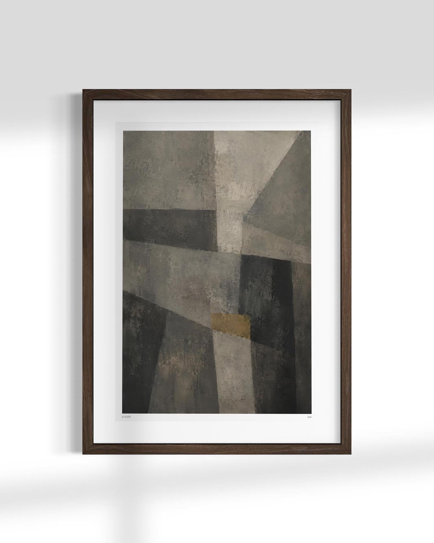 Framed abstract wall art featuring a geometric composition in shades of gray, black, and beige with a small gold accent, displayed in a dark wood frame with a white mat against a light gray wall.