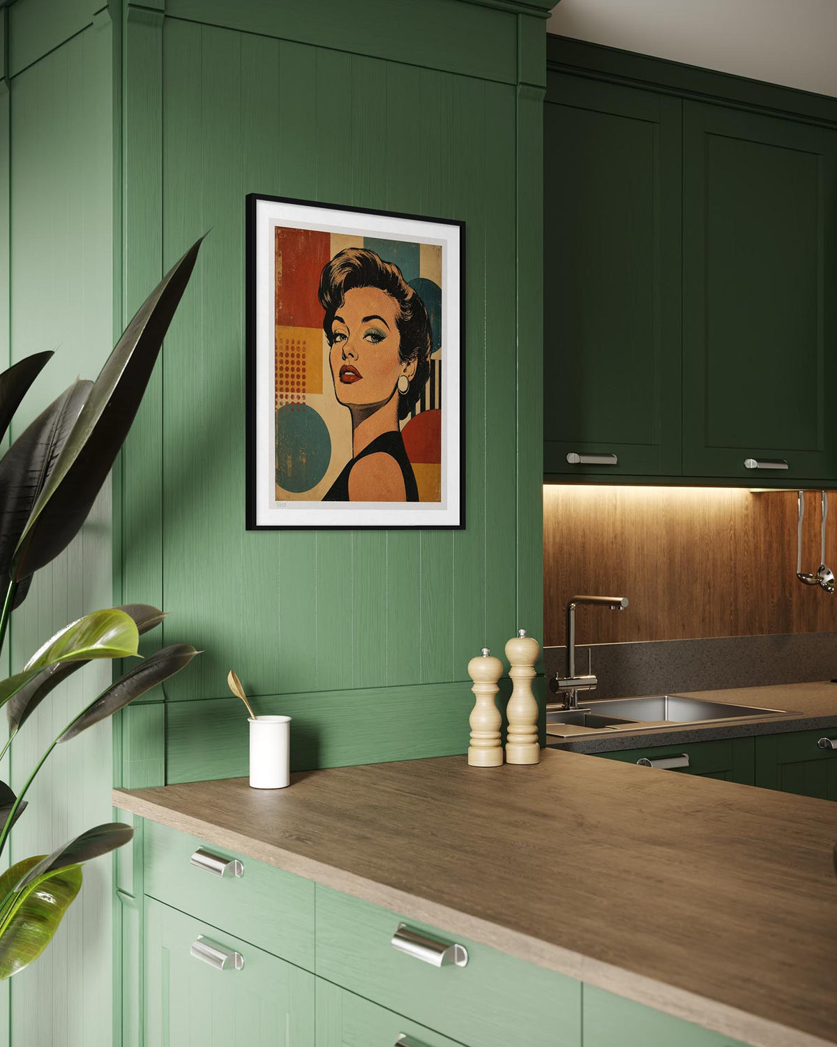 A framed pop-art portrait print of Marilyn Monroe hangs on a dark green kitchen wall above a wooden countertop. The kitchen features matching green cabinets, a wood backsplash, and modern stainless steel handles.