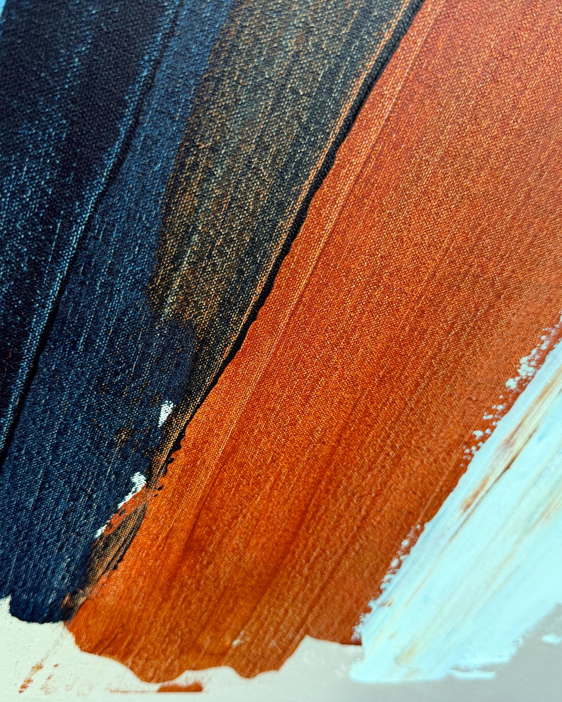 Abstract painted brushstrokes in dark navy blue, warm rust orange, and pale icy blue on a textured canvas surface.