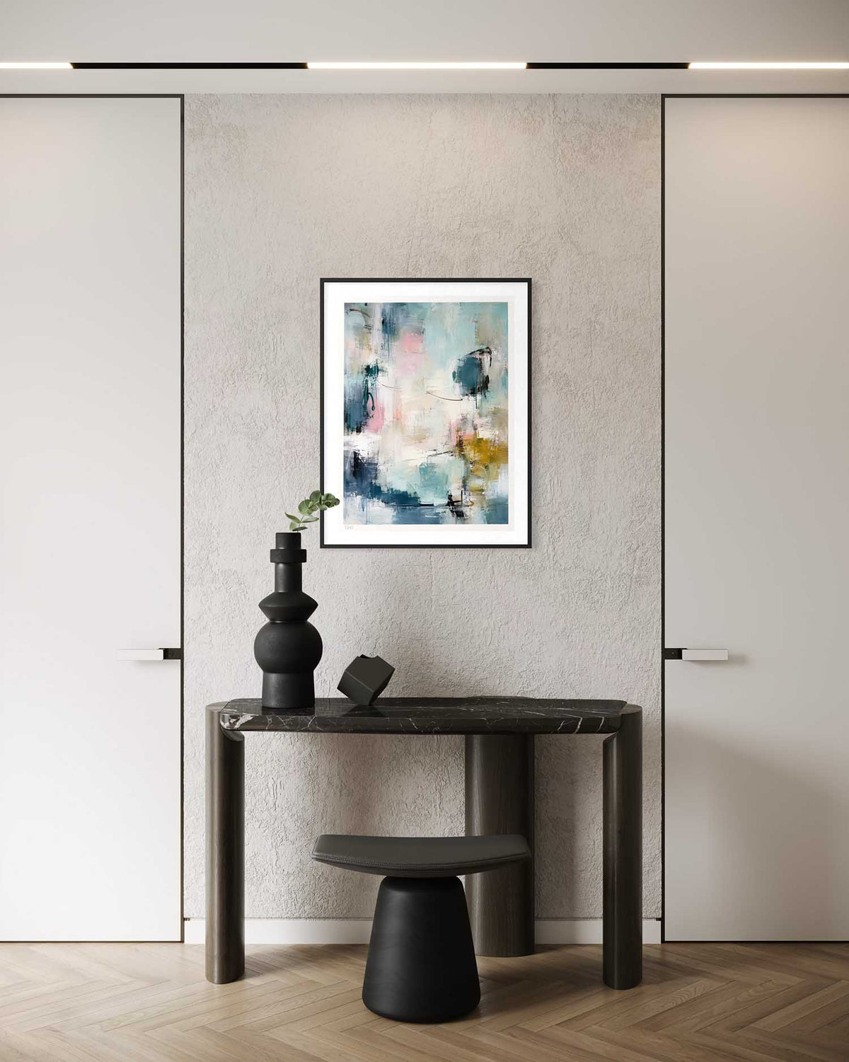 A framed abstract art print with blue, white, and yellow brushstrokes hangs on a textured light gray wall above a dark wood console table and black stool in a modern interior.