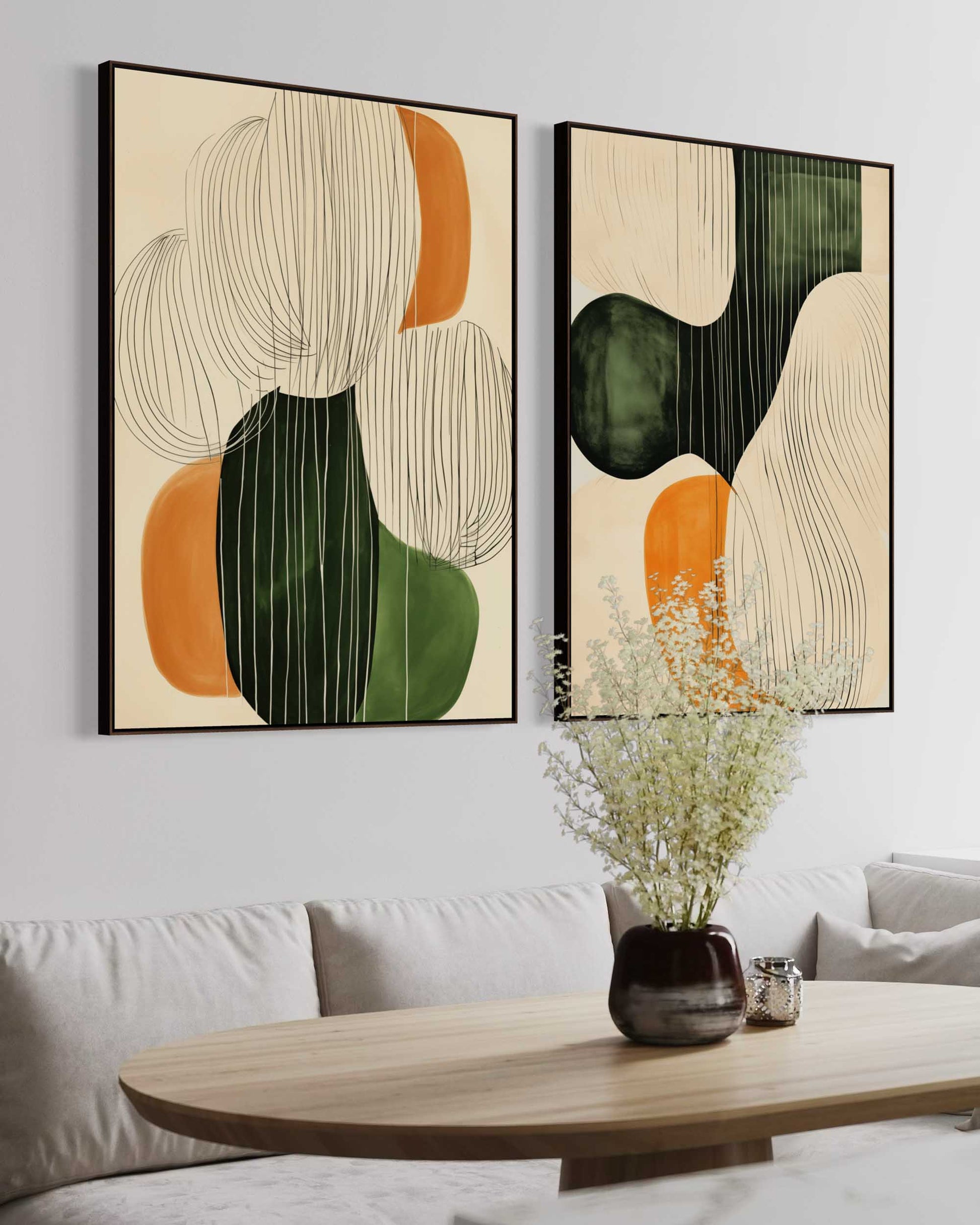 Two abstract art pieces on a wall above a sofa with a vase and candle on a coffee table.