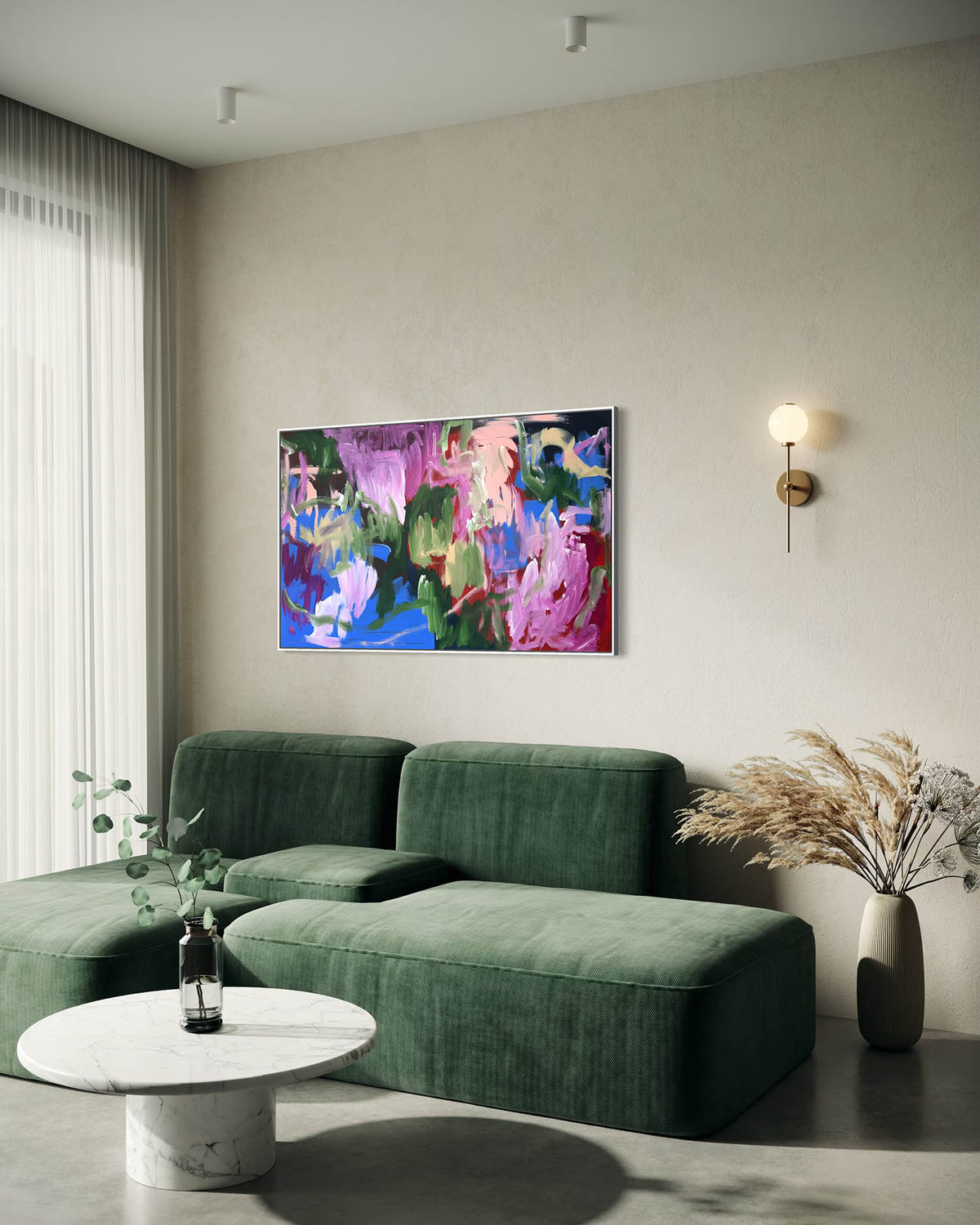 A modern living room setting featuring a vibrant abstract canvas painting with pink, blue, and green brushstrokes, hung on a textured beige wall above a green velvet sectional sofa.
