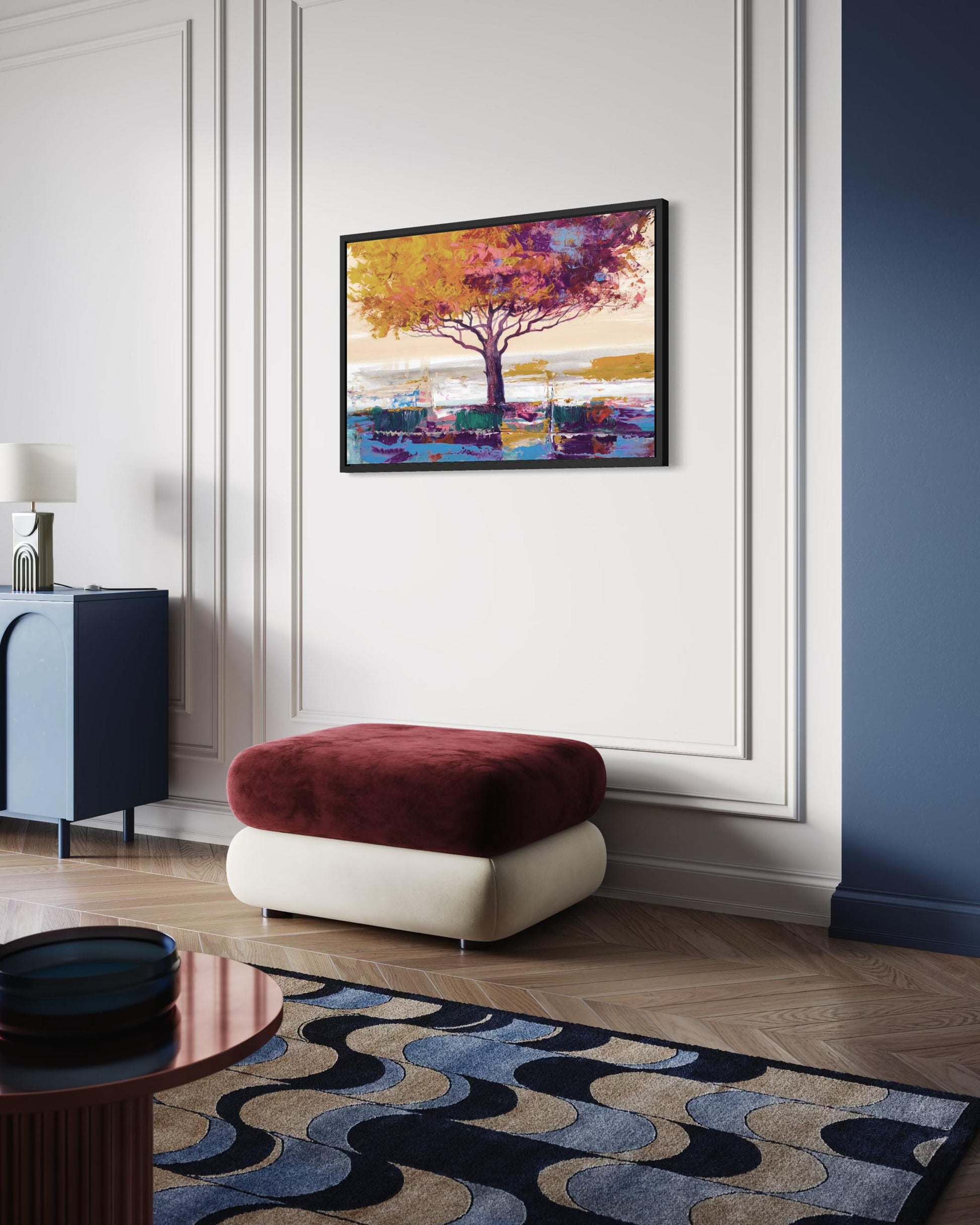 Colorful abstract tree painting on a white wall above a red and white ottoman in a modern living room.