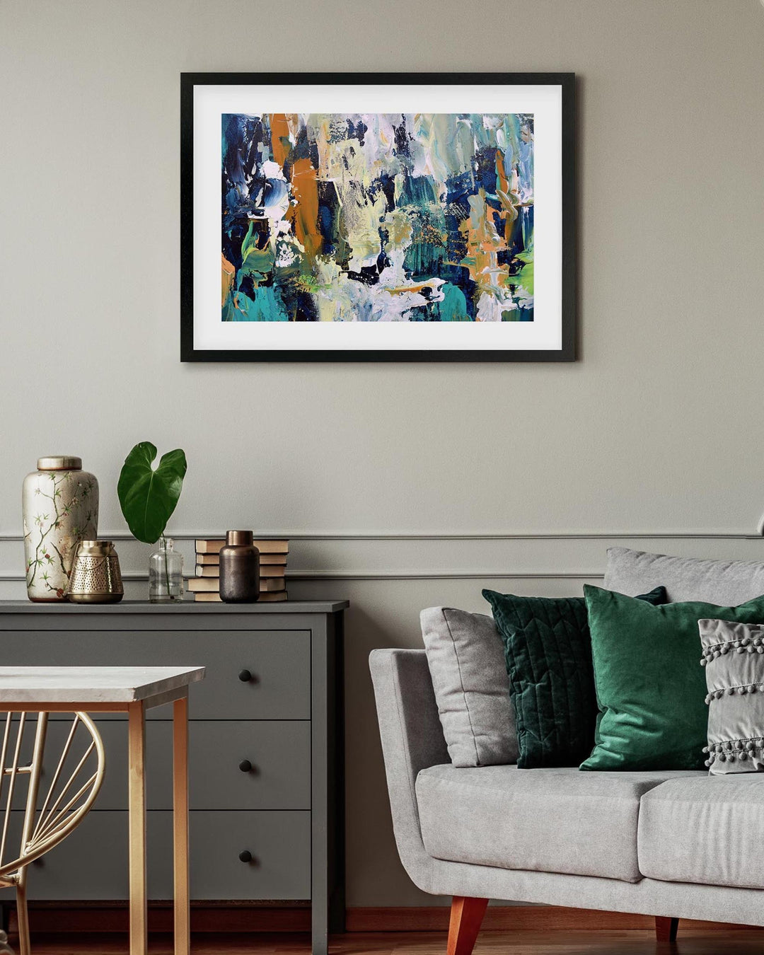 Framed abstract painting on a wall above a sofa and side table in a living room.