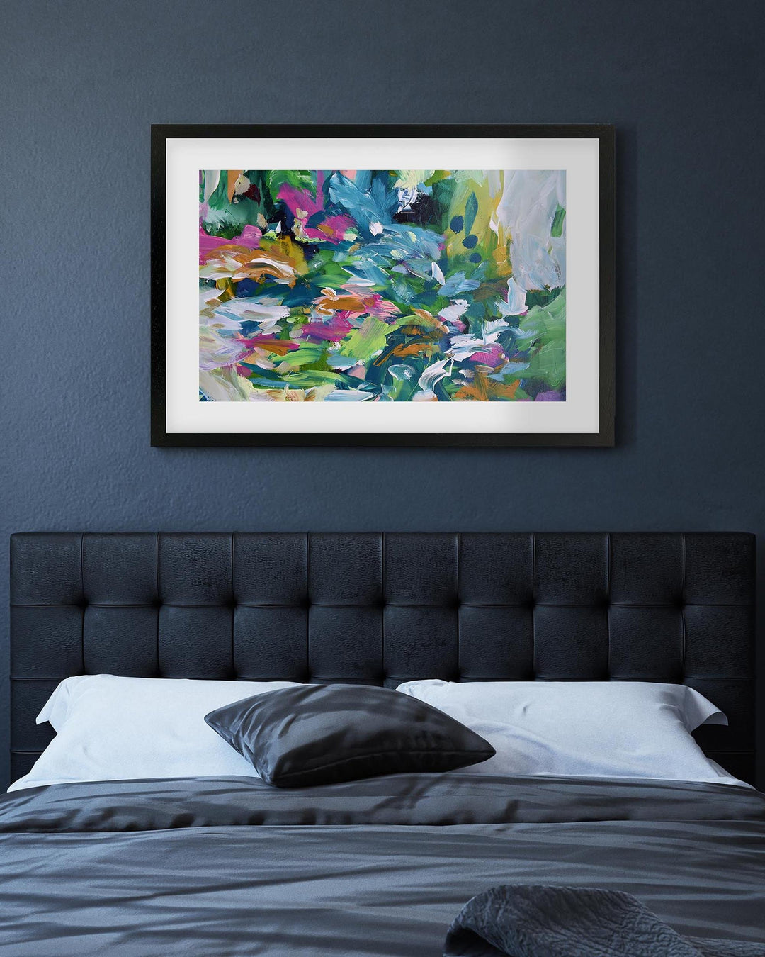 Bedroom with a black upholstered headboard and abstract art on the wall.