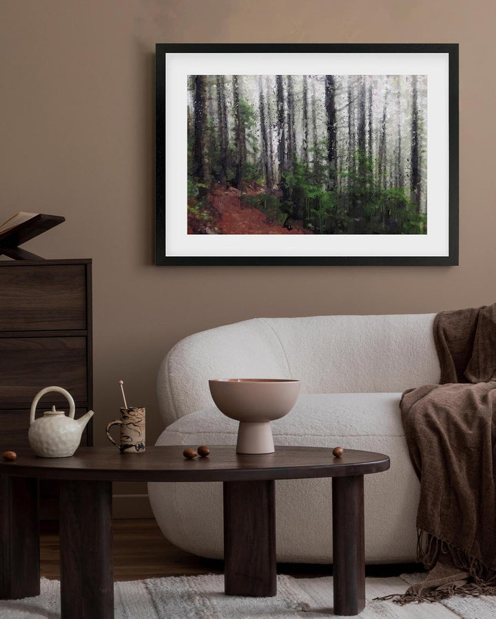 Framed forest print on a wall above a sofa and coffee table in a living room.