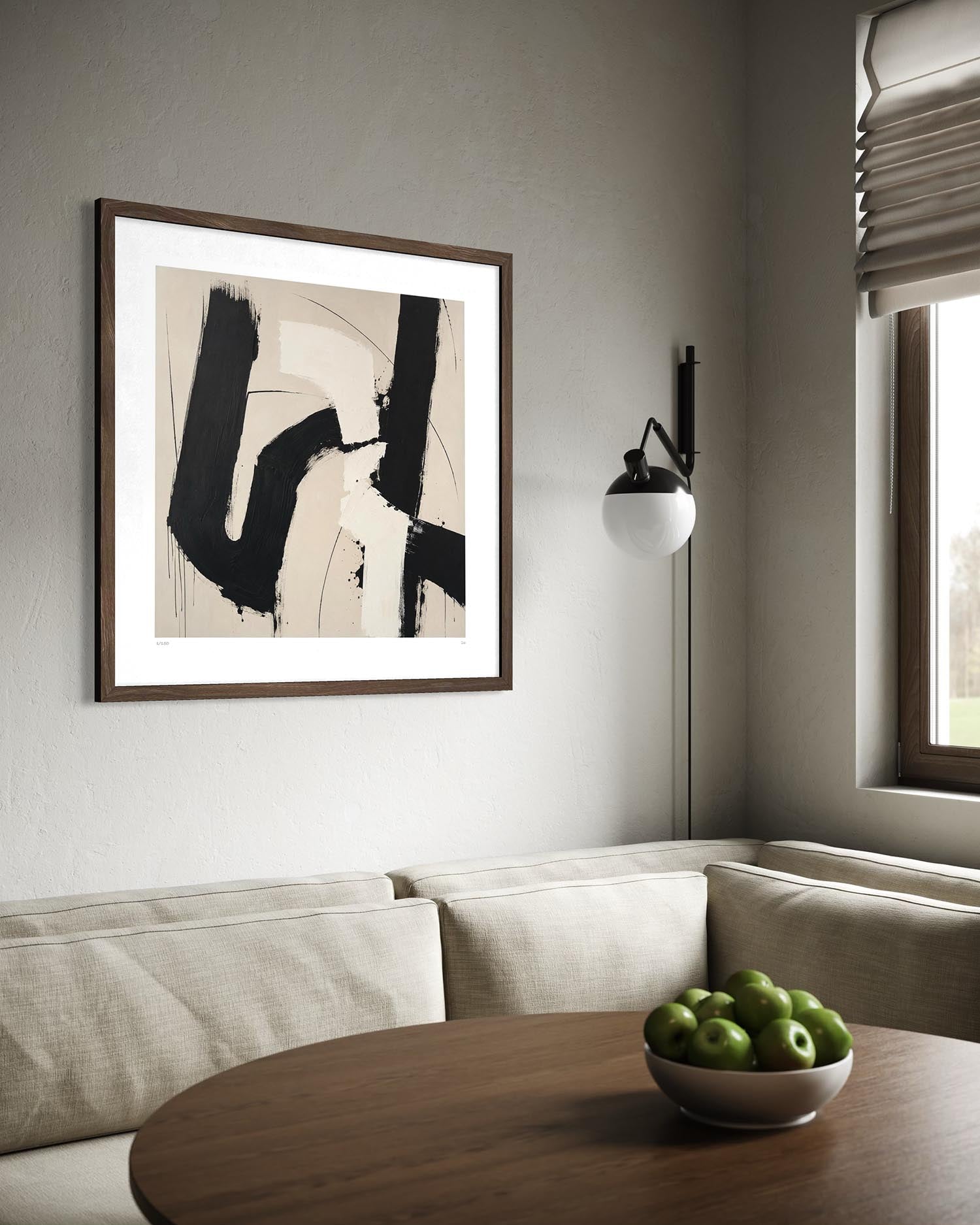 Framed abstract wall art hanging above a beige sofa in a modern living room. The artwork features bold black brushstrokes on a warm beige background, enclosed in a dark wood frame with a wide white mat.