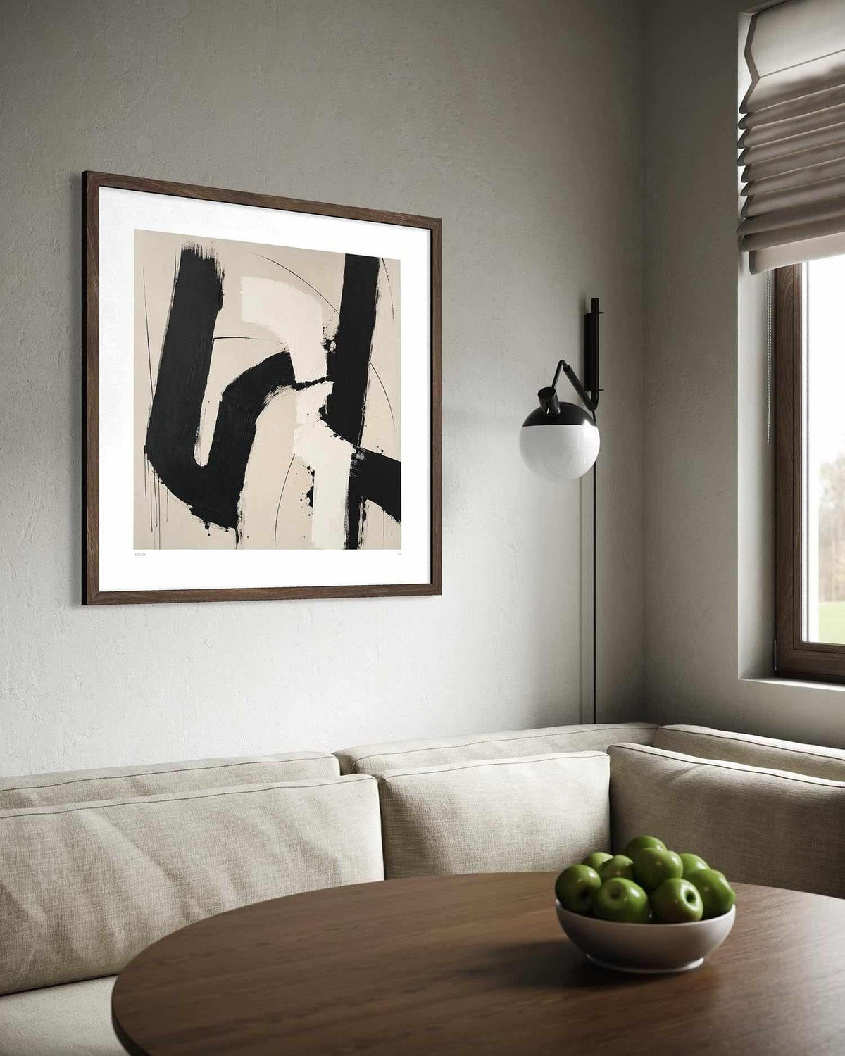 Framed abstract wall art hanging above a beige sofa in a modern living room. The artwork features bold black brushstrokes on a warm beige background, enclosed in a dark wood frame with a wide white mat.