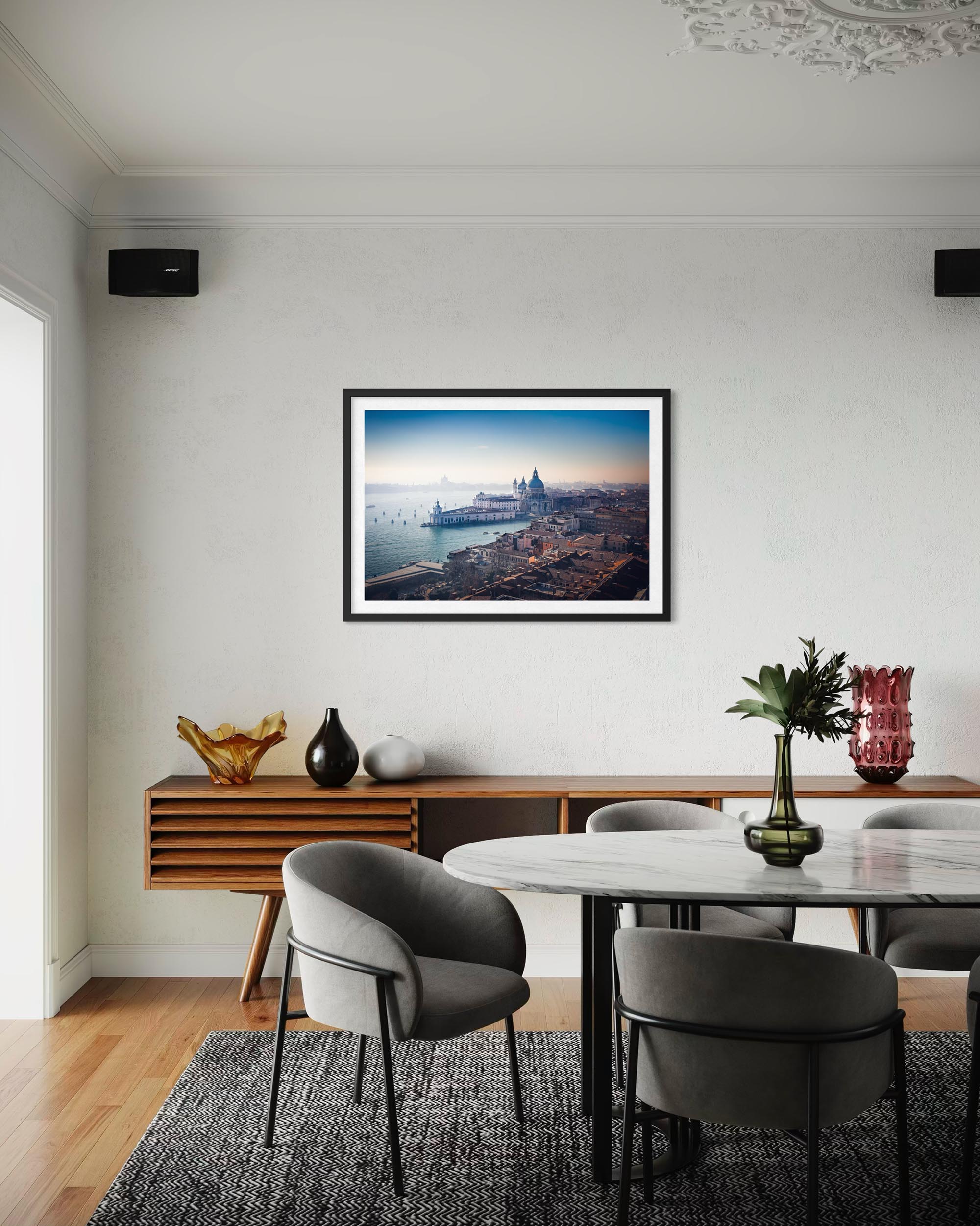 Dining room with a framed picture of a cityscape on the wall, wooden table, and chairs.