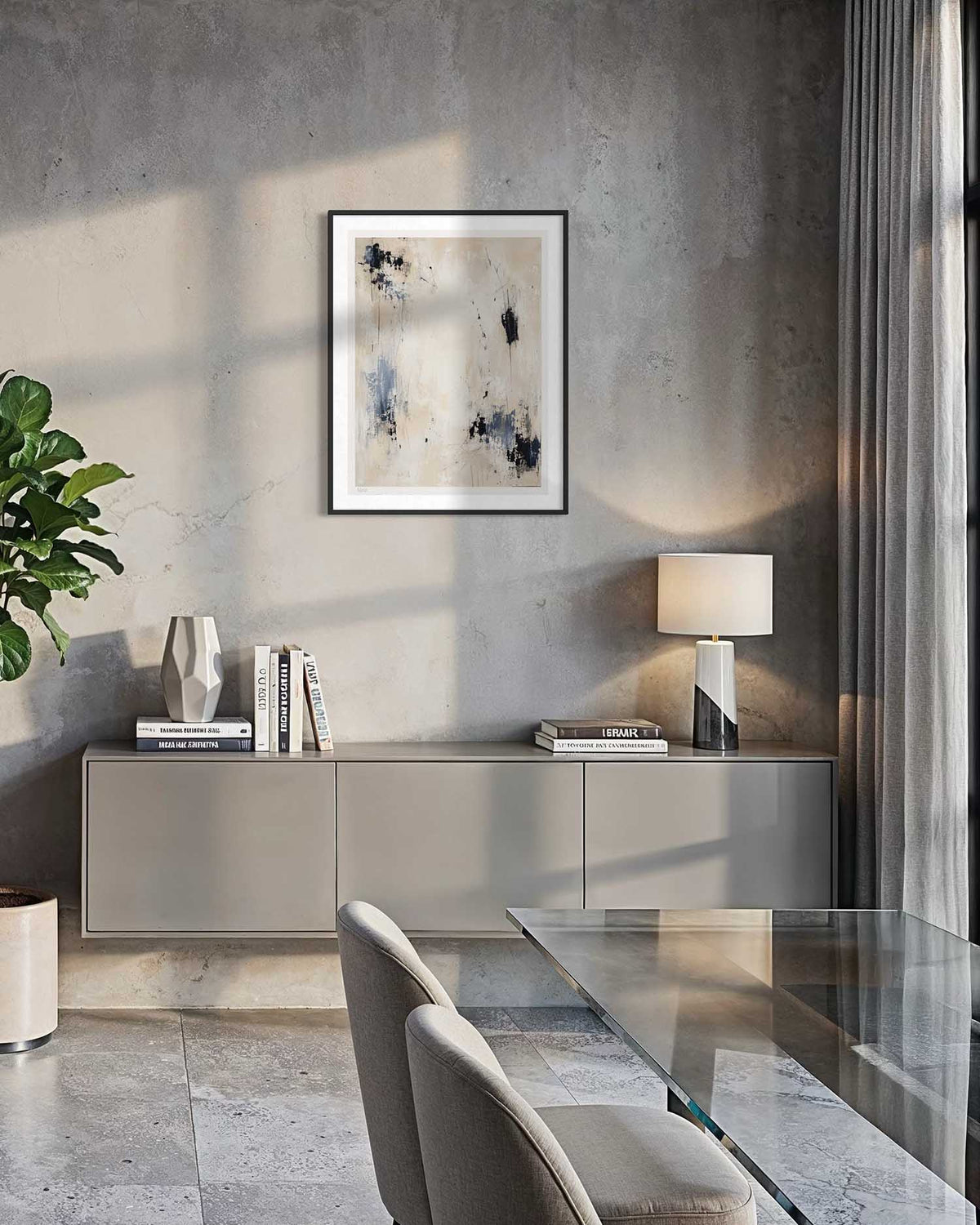 A framed abstract art print with black, blue, and beige brushstrokes hangs on a textured gray wall in a modern dining room setting with a glass table, gray chairs, and a sideboard.