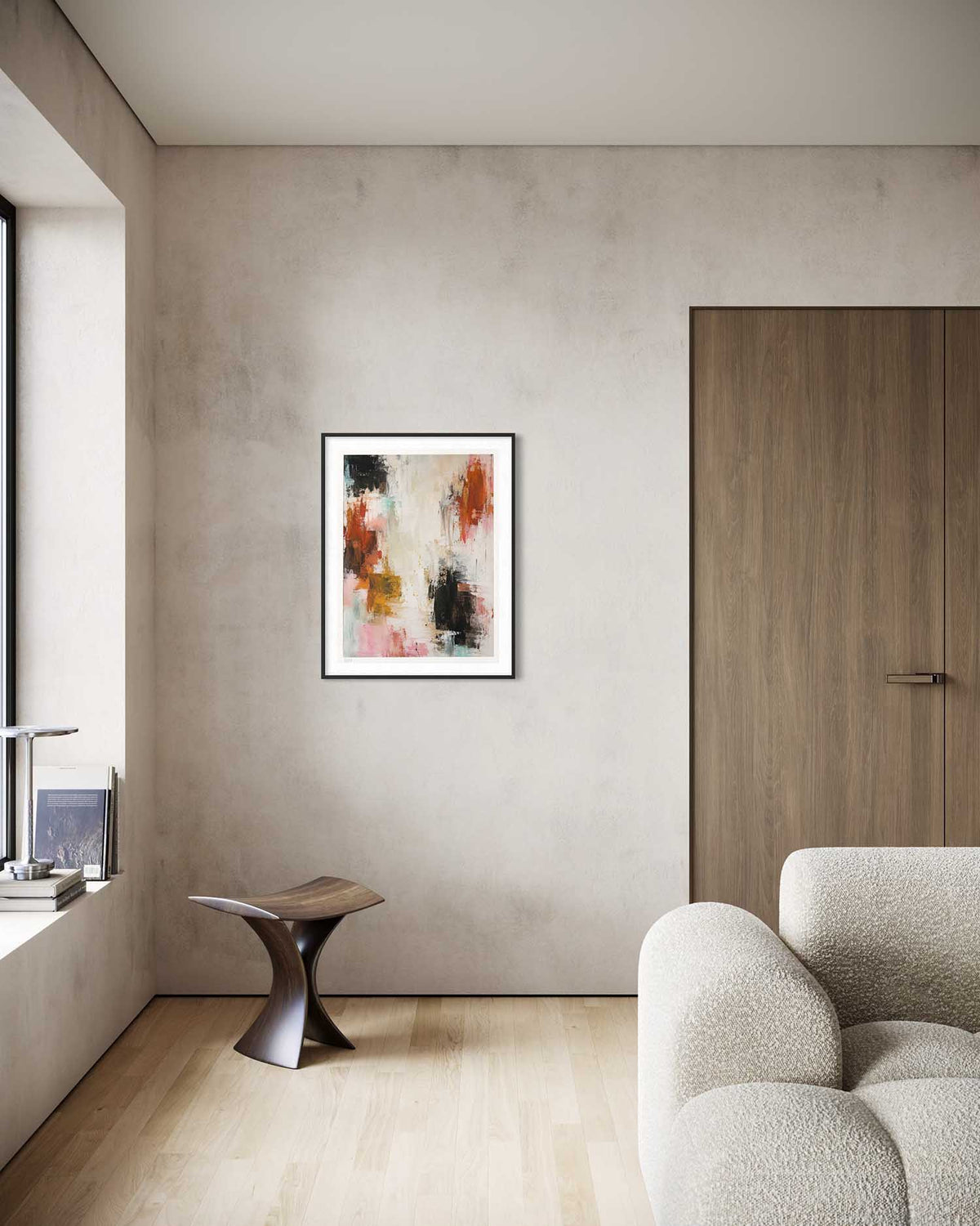 An abstract framed art print hangs on a textured beige wall in a modern living room setting with a wooden door, a small sculptural side table, and a textured armchair.