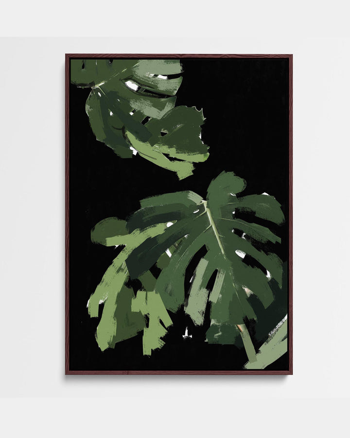 A framed canvas artwork depicting a monstera leaf with a black background and green accents, presented in a portrait orientation.
