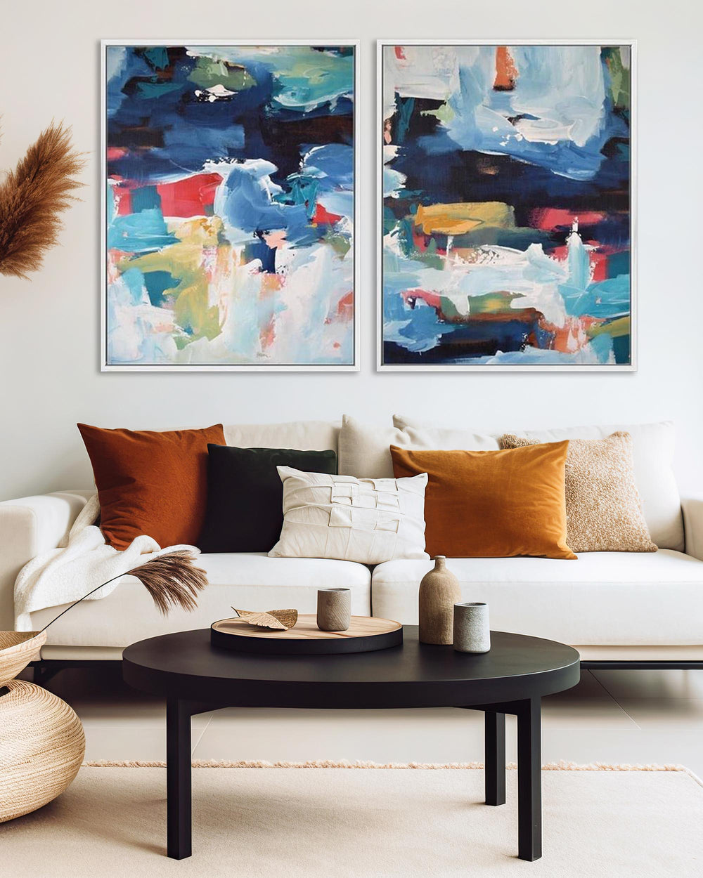 A set of two abstract canvas paintings featuring geometric patterns in blue, black, and colorful tones, displayed above a white sofa in a living room setting.