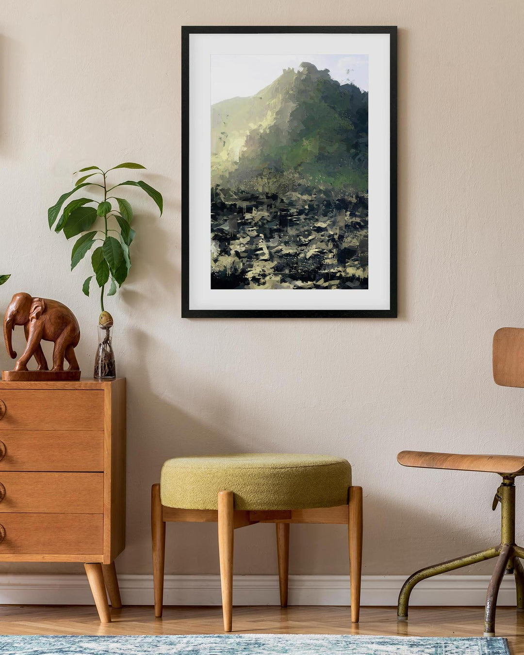 Framed landscape print on a wall above a wooden dresser with decorative items.