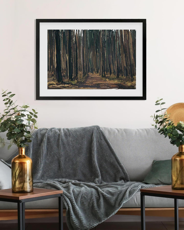 Framed artwork of a forest scene above a gray sofa with decorative elements.