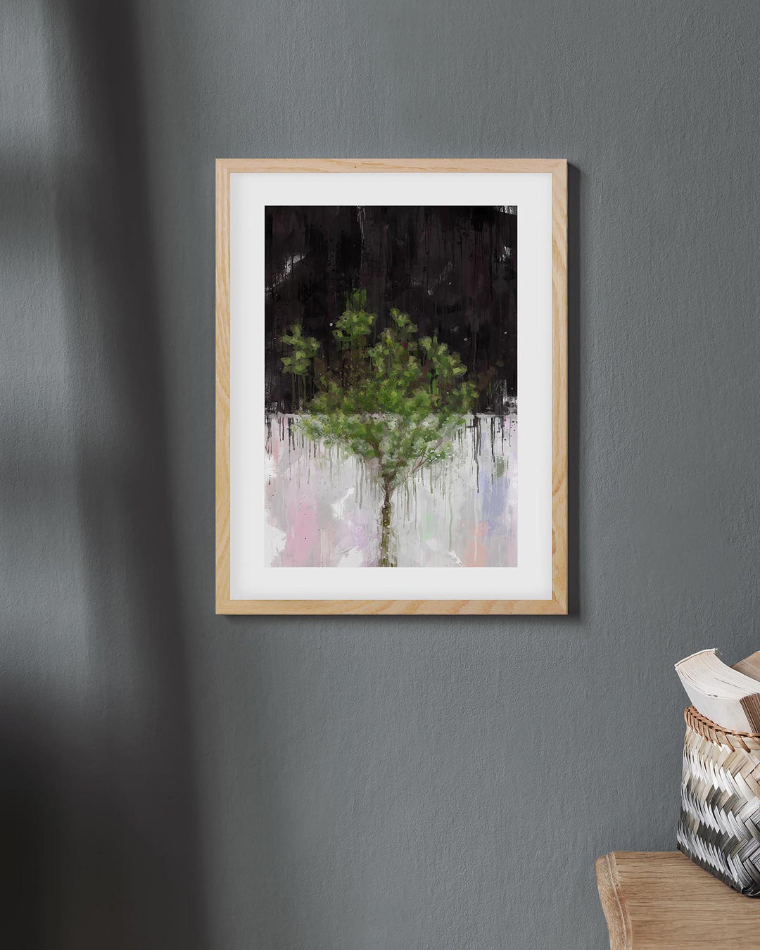 Framed artwork of a tree on a gray wall with a basket on a chair below.