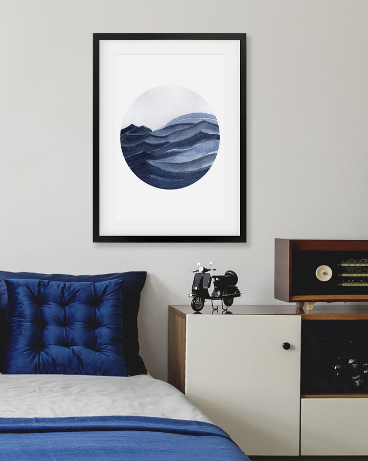 Framed abstract art piece on a wall above a bed with blue bedding.