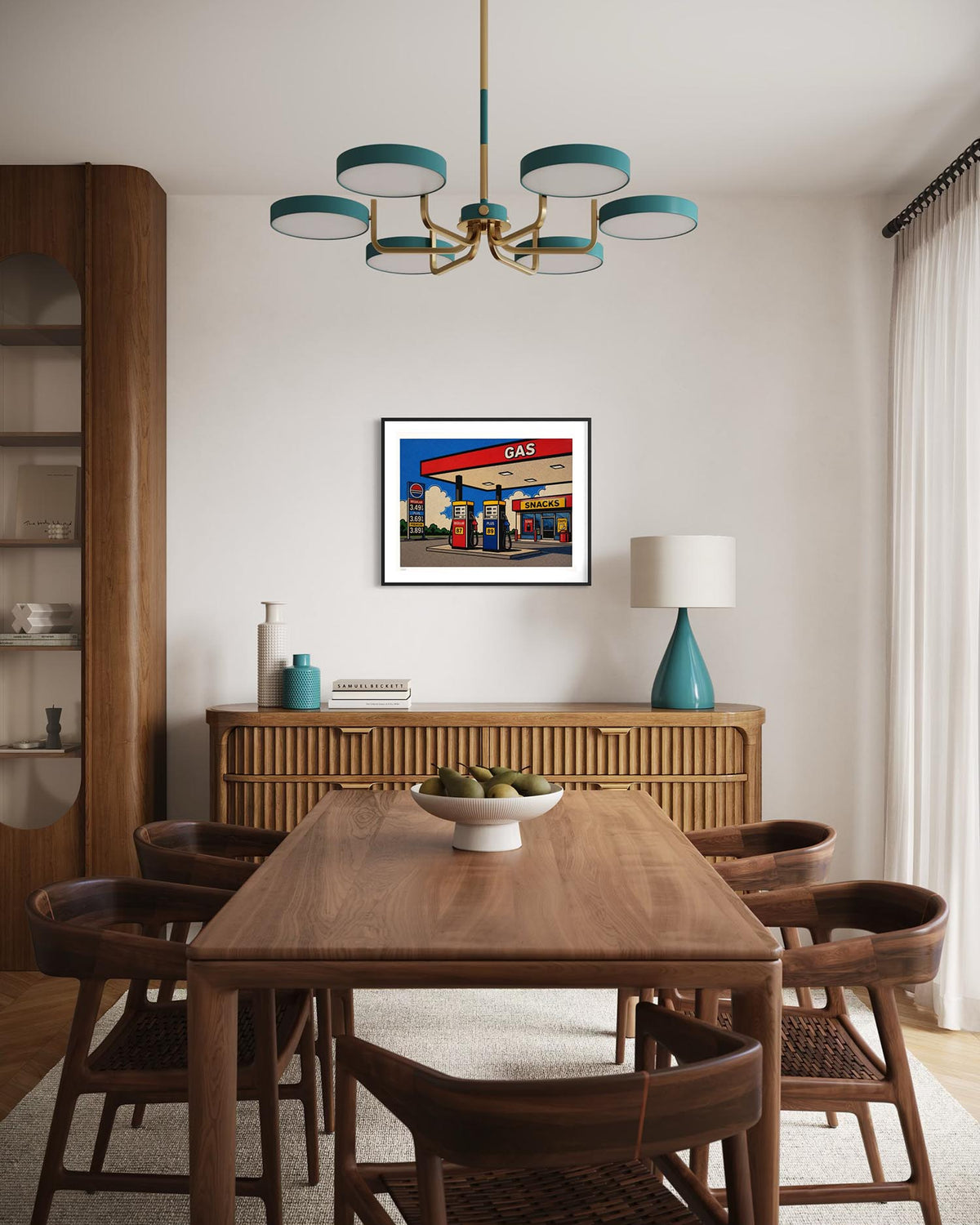 A framed art print depicting a vintage gas station scene hangs on a beige wall in a modern dining room setting with a wooden dining table, chairs, and a teal chandelier.