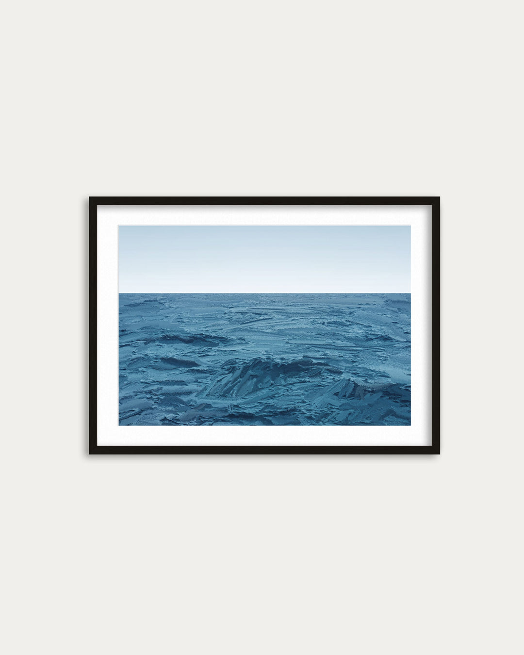 Framed artwork of a blue ocean scene on a white wall