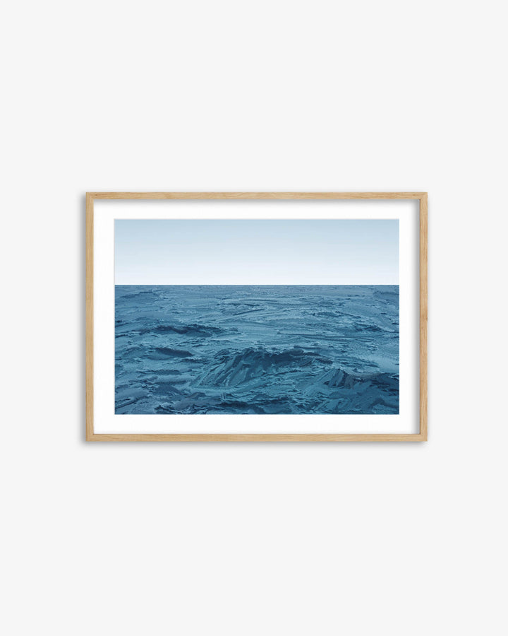 Framed artwork of a blue ocean scene on a white wall