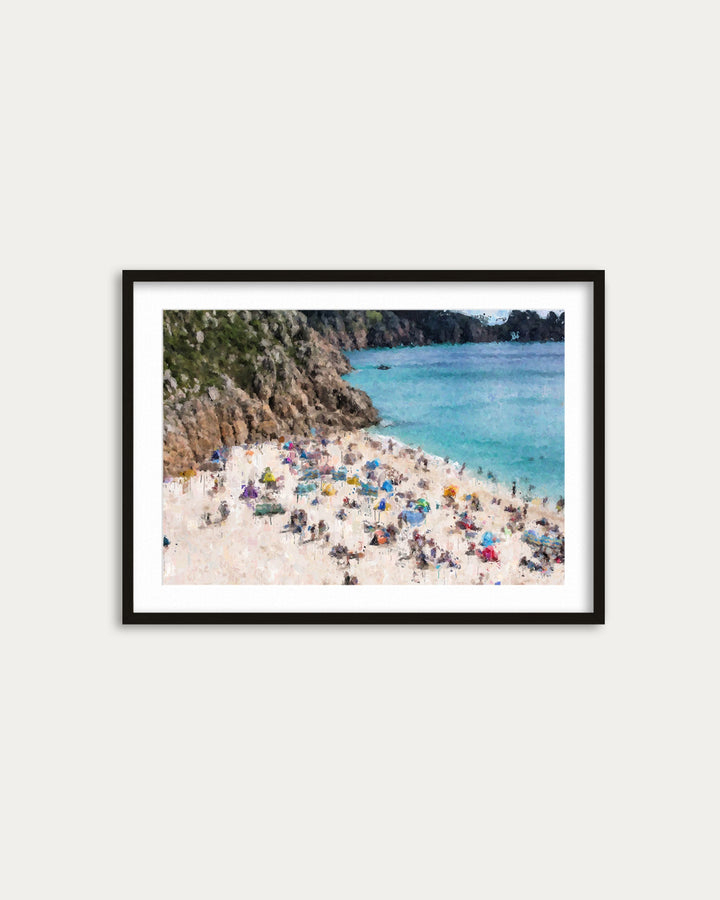 Framed photograph of a beach with people and cliffs on a white wall