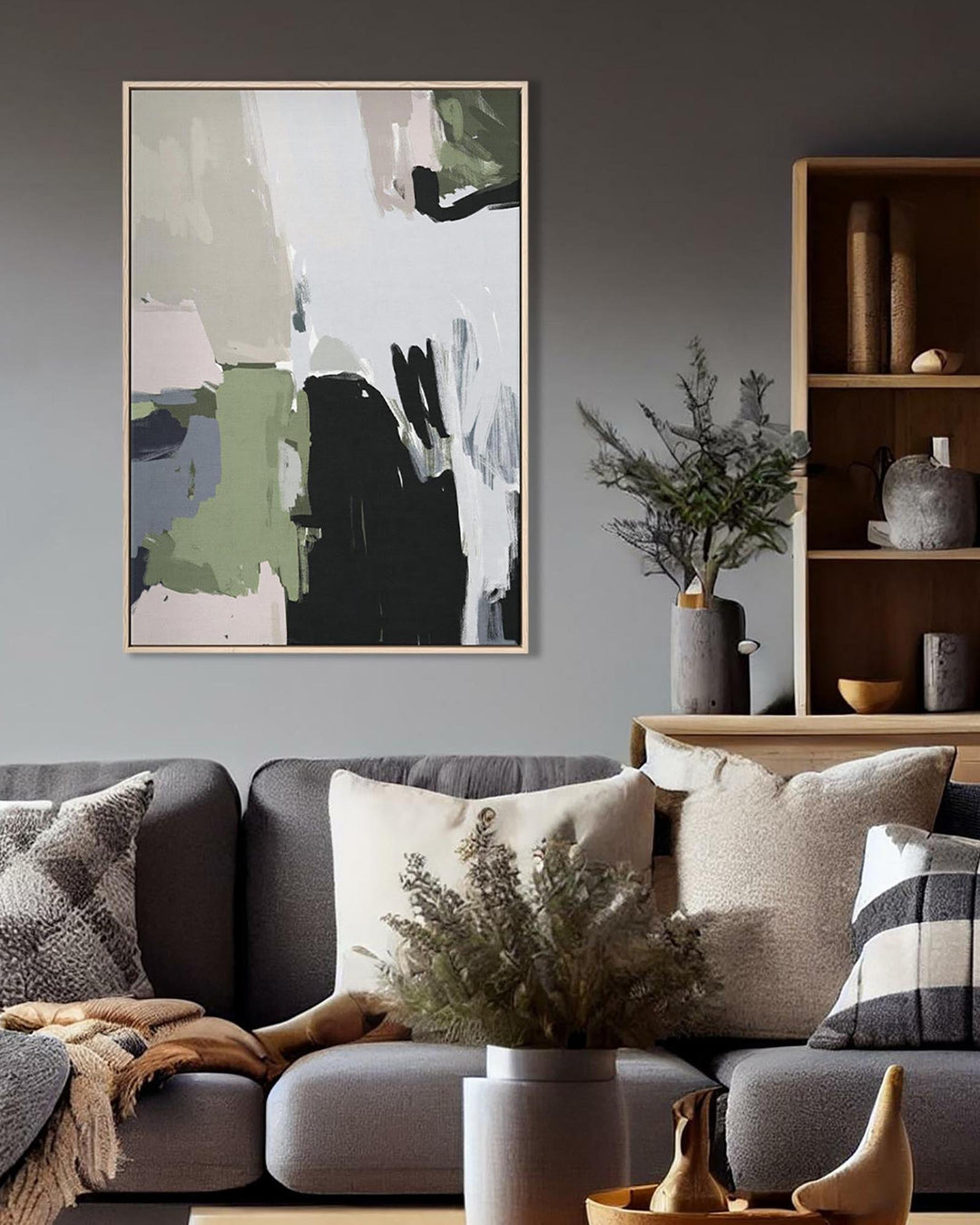 Living room with a gray sofa, abstract art on the wall, and decorative items.