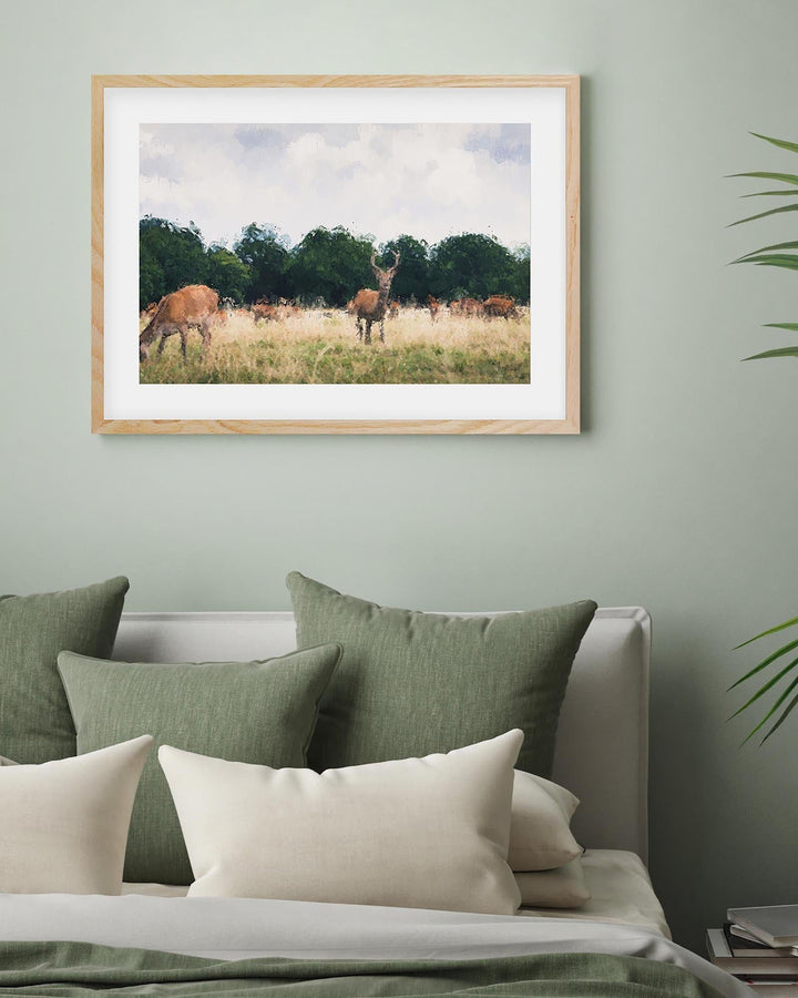 Framed artwork of deer in a field above a bed with green and white pillows.
