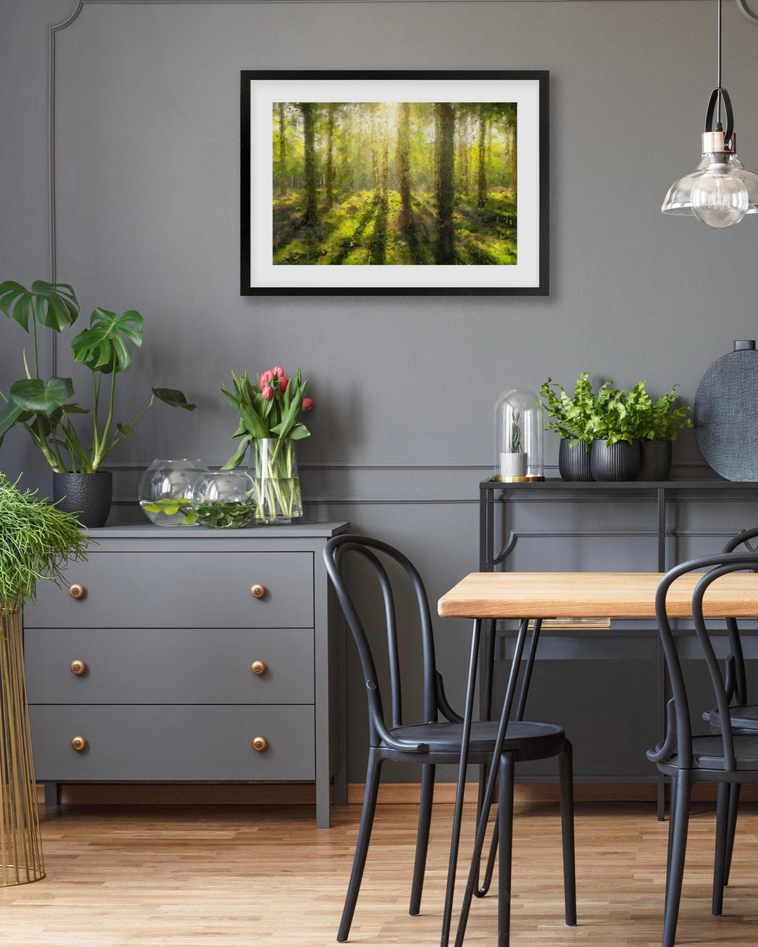 Dining room with a gray wall, framed forest picture, and a wooden table.