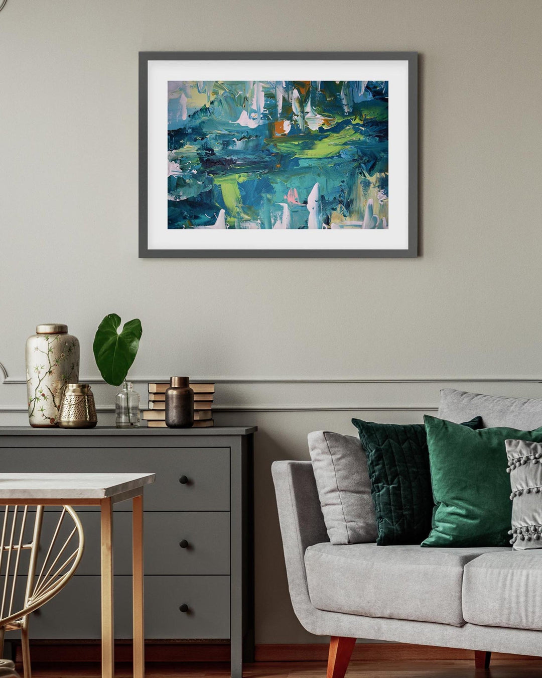 Living room with a framed abstract painting on the wall, a sofa with pillows, and a side table.