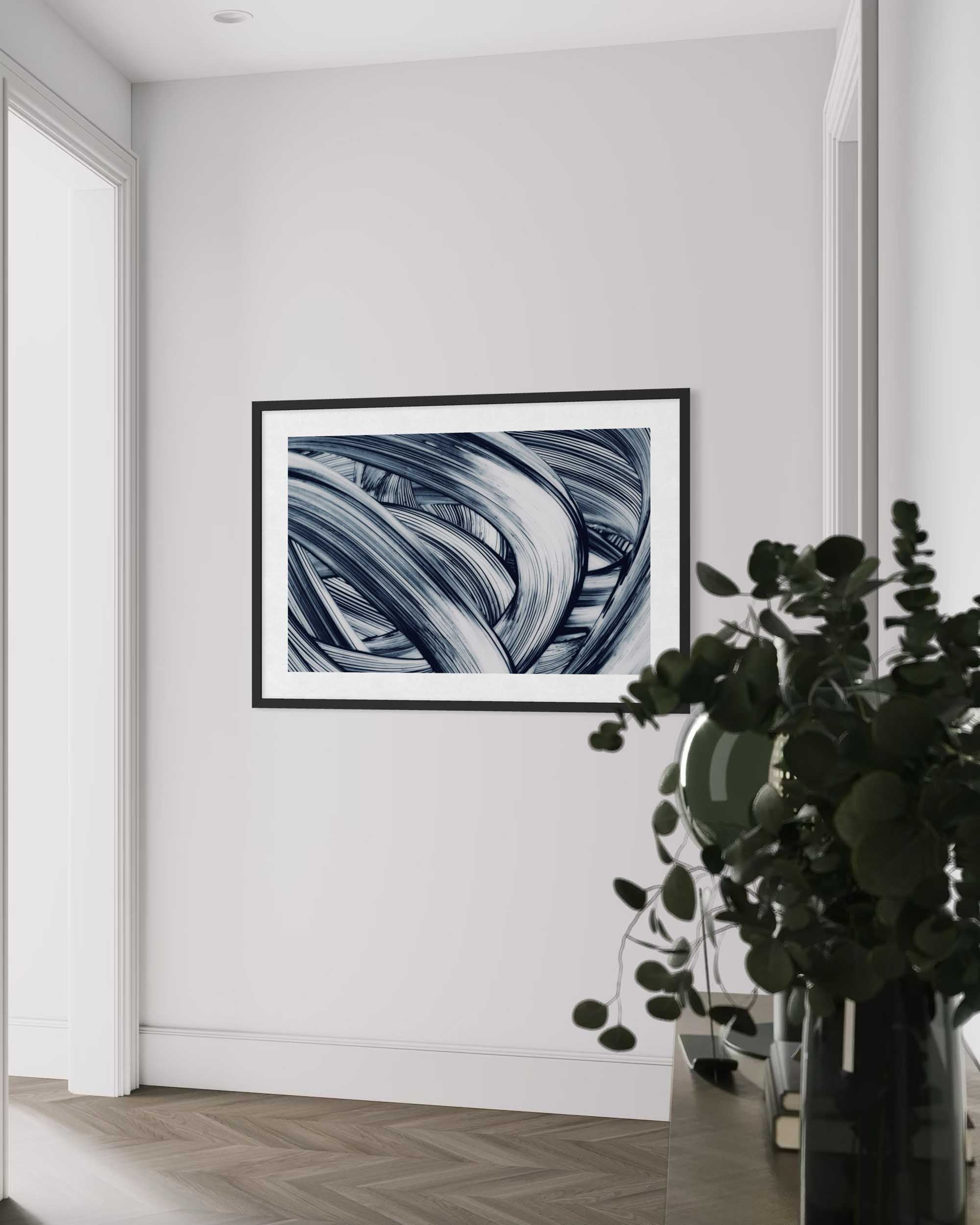 Framed abstract art on a white wall with a plant in the foreground