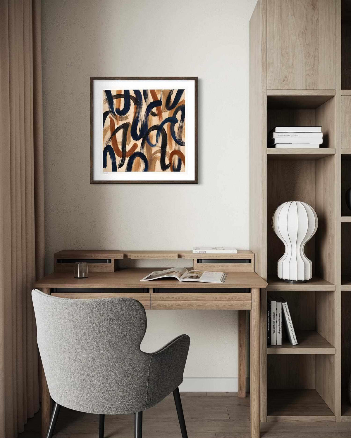 A framed abstract art print with flowing black and brown lines on a warm beige background, displayed on a wall above a wooden desk with a gray upholstered chair in a modern home office setting.