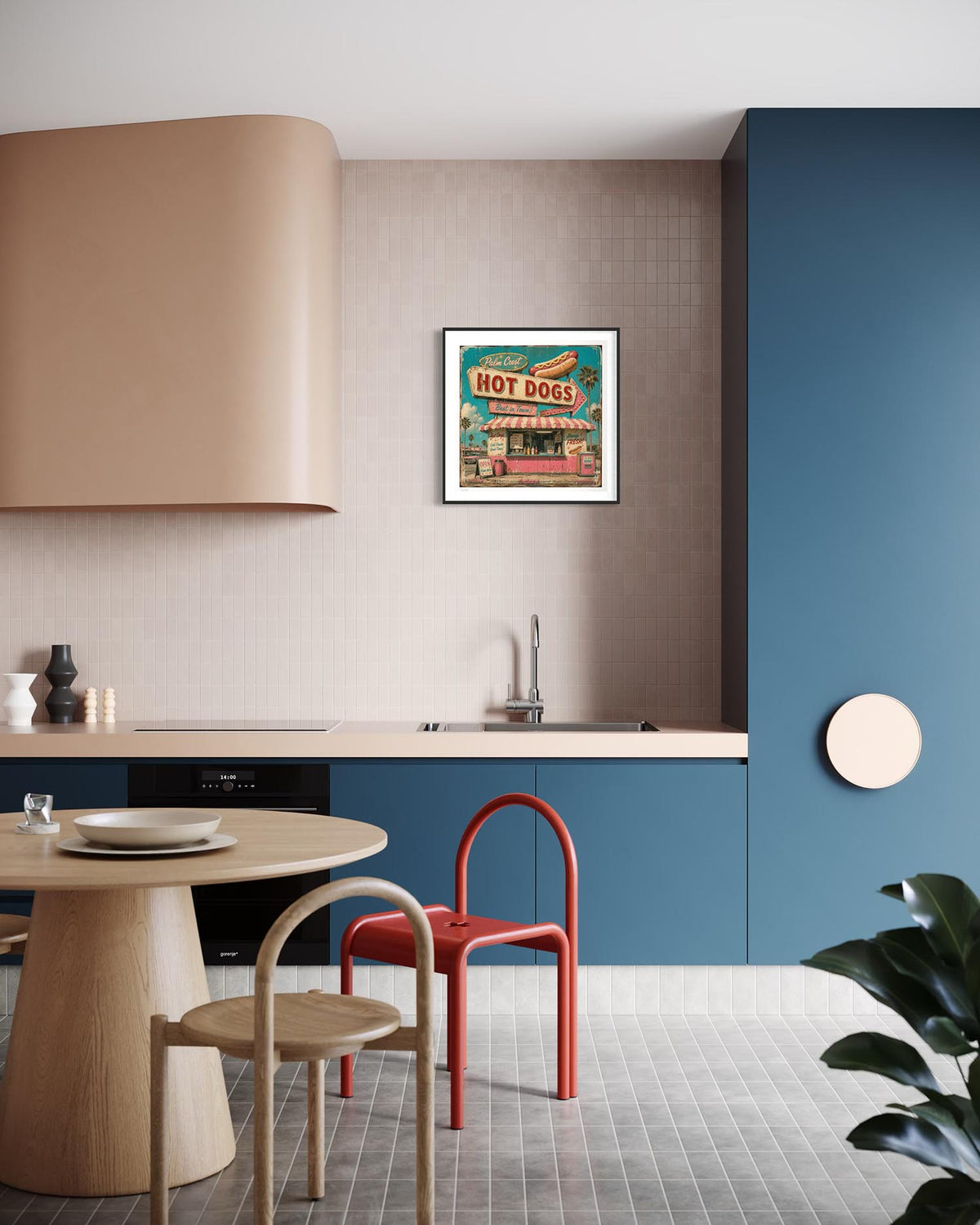 A framed vintage-style 'Hot Dog' street art print hangs on a textured beige wall in a modern kitchen setting with blue cabinets, a wooden dining table, and a red chair.
